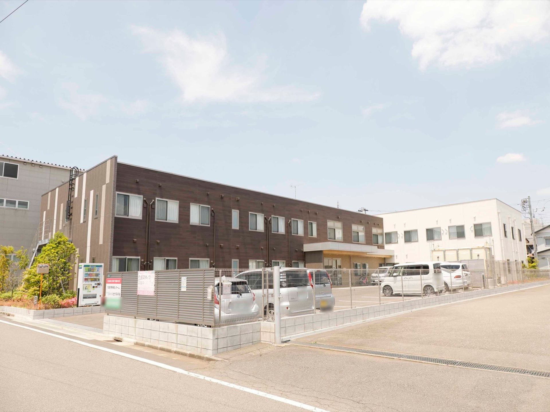 建物は２階建てで、極力上下の移動がない造りとなっている。施設の前は駐車台数をたくさん確保した駐車場になっている。