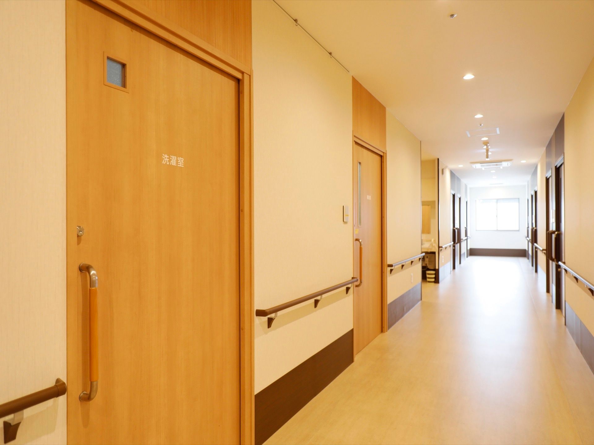 廊下の突き当たりに窓が開いており、外光が差し込んでいる。居室のドアが両側に並んでいる。洗濯室がある。
