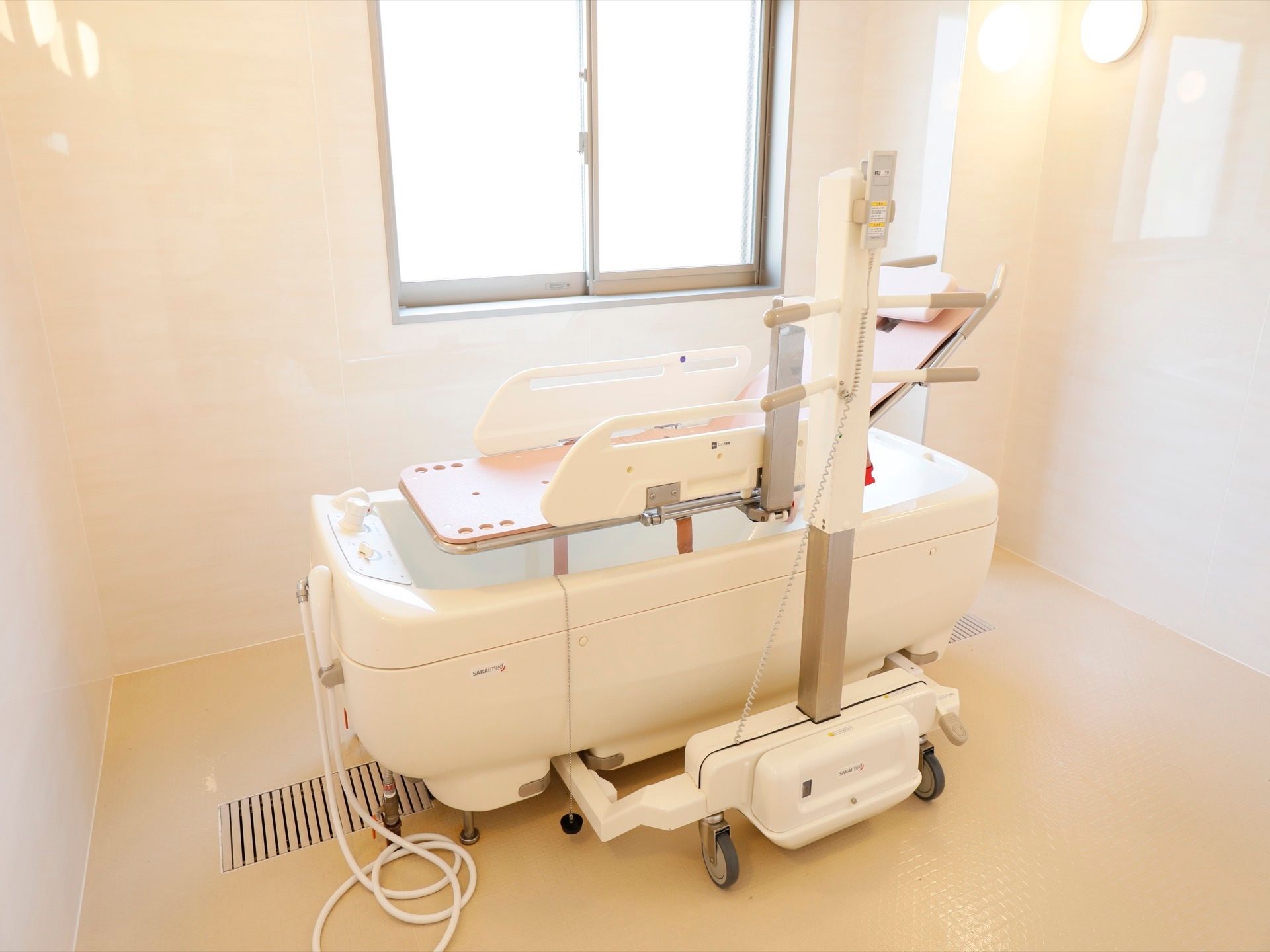 個浴用浴室は掃除が隅々まで行き届き、真っ白に維持されている。特殊浴槽とストレッチャーが置かれている。