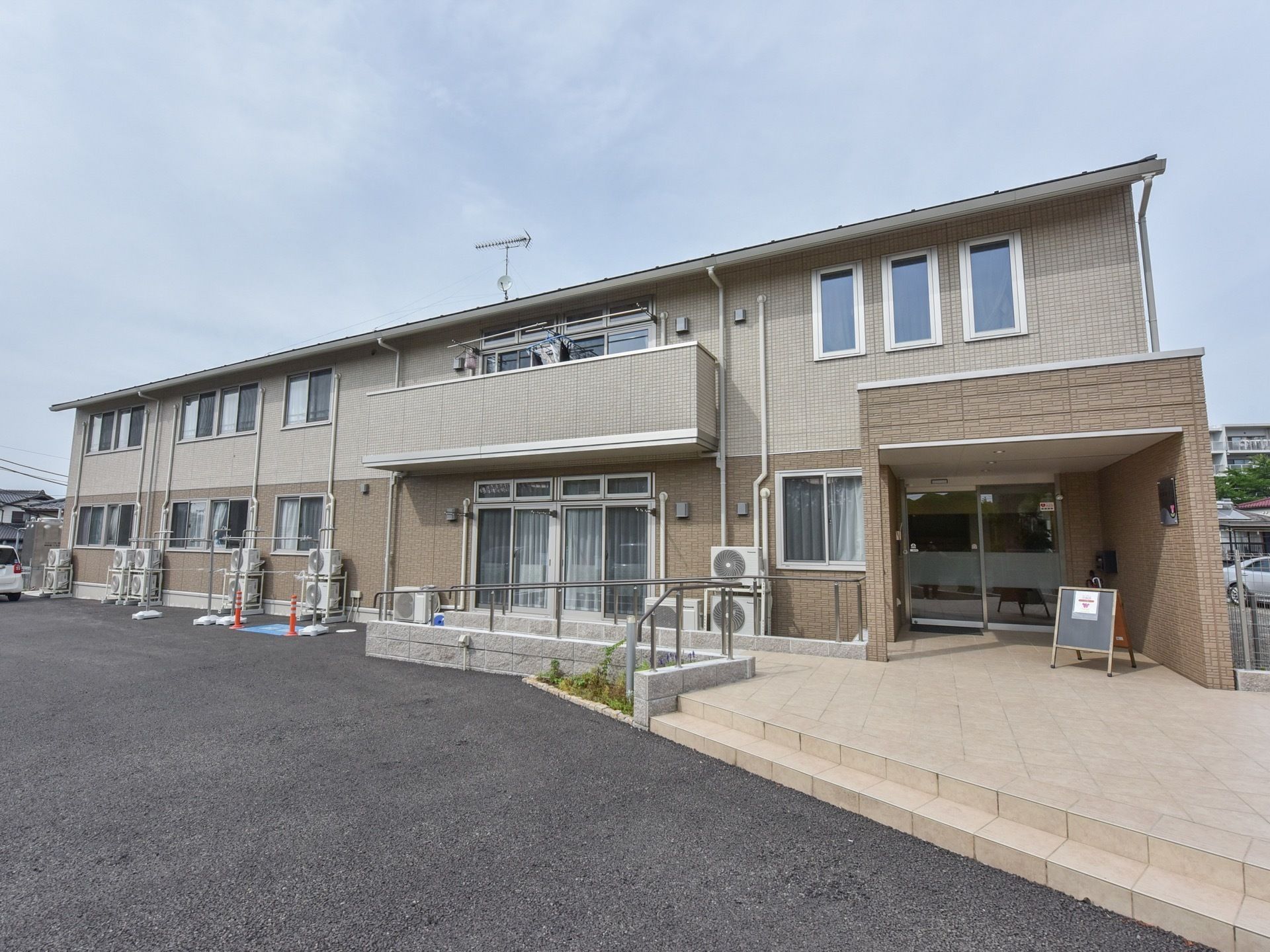 施設は２階建てである。玄関前には手すりが設置されている。階段のほか、スロープも設けられており、バリアフリー対応となっている。