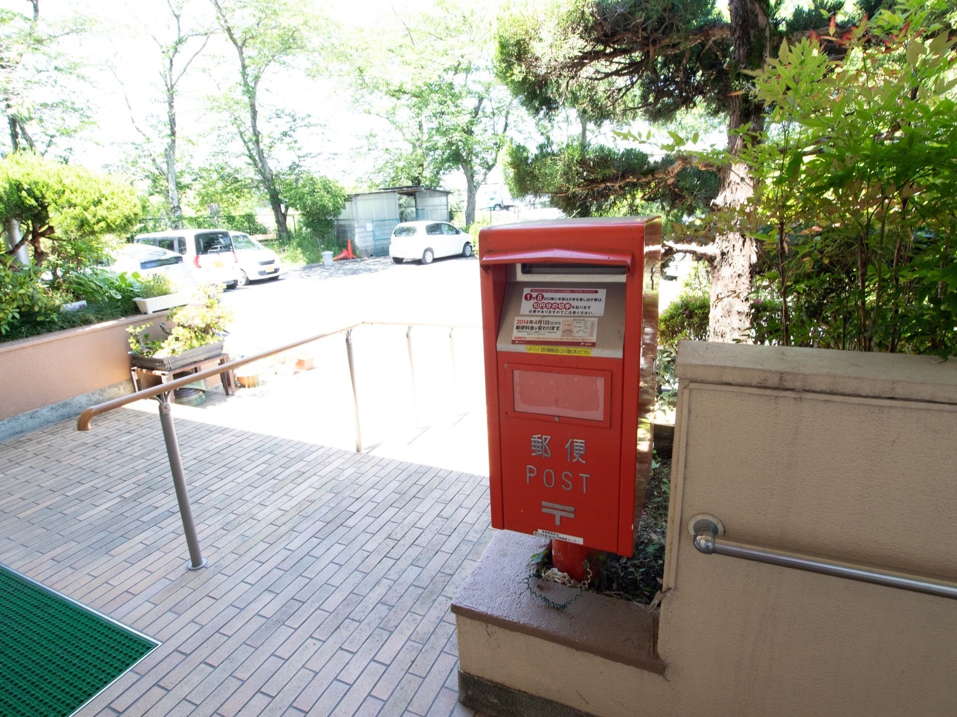 施設のエントランスには植え込みがあり、その一角にポストが設置されている。ポストの手前まで手すりが設置されているので安心して移動できる。