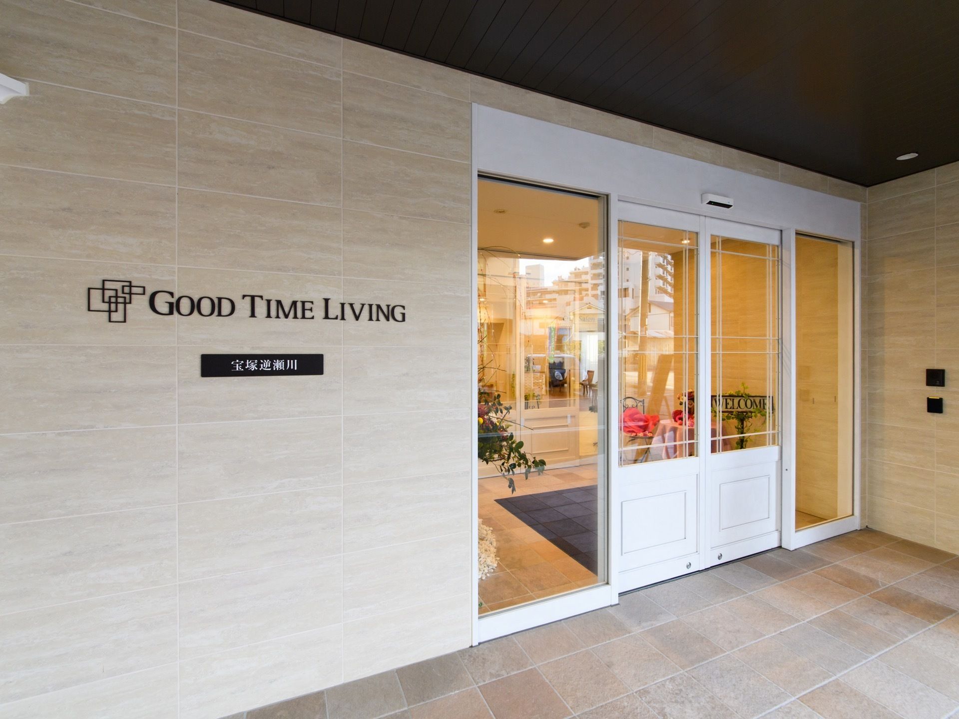 ガラス張りの入口ドアからはおしゃれな中の様子が見える。ドア横の壁にはローマ字で施設名が表示してある。