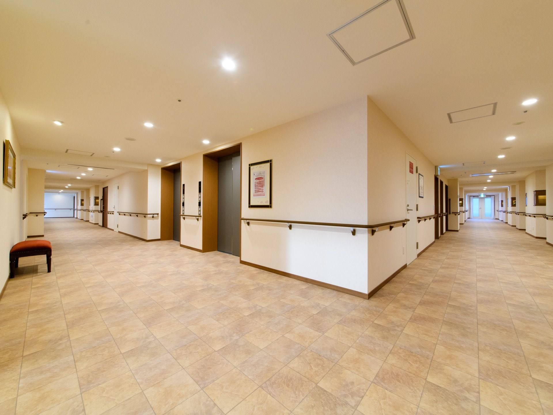 大理石風デザインの四角いタイルが、床全体に敷き詰められている。白い壁の両側には、長い手すりが取り付けられている。