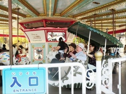 レクリエーションで訪れた遊園地で、メリーゴーランドに乗りポーズをとる入居者様