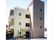 ３階建ての建物の背後に４階建ての建物が設けられている。屋根付きの玄関の近くには緑の木が植えられている。