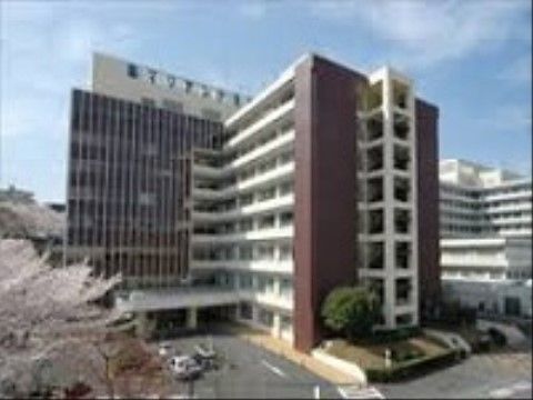 大きな大学病院の建物は8階建てになっており、１階の玄関には屋根が設けられている。屋上には大きな看板があり、病院名が表示されている。