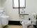 白を基調とした内装に、壁の下側と手すり、窓枠に黒を取り入れたトイレである。便座の正面に深さのある洗面台を設置している。