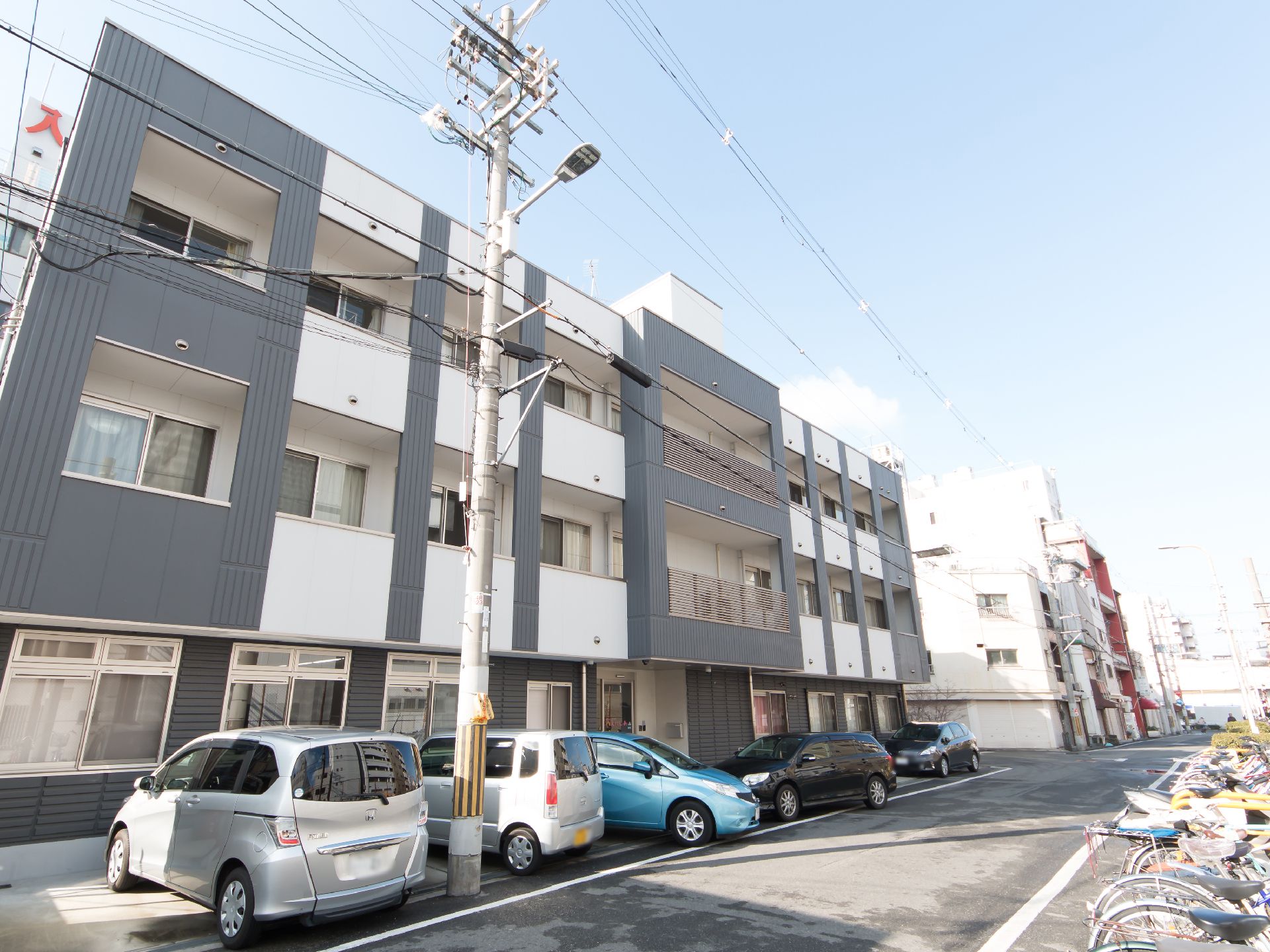 住宅街の中にあるホーム。白と黒を基調としたお洒落な建物で、道路を挟んで向かい側に駐輪スペースが設けられている。