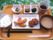 食事のメニューの一例である。膳の上には、茶碗によそわれたご飯、エビフライ、小鉢、漬物、味噌汁などが置かれている。