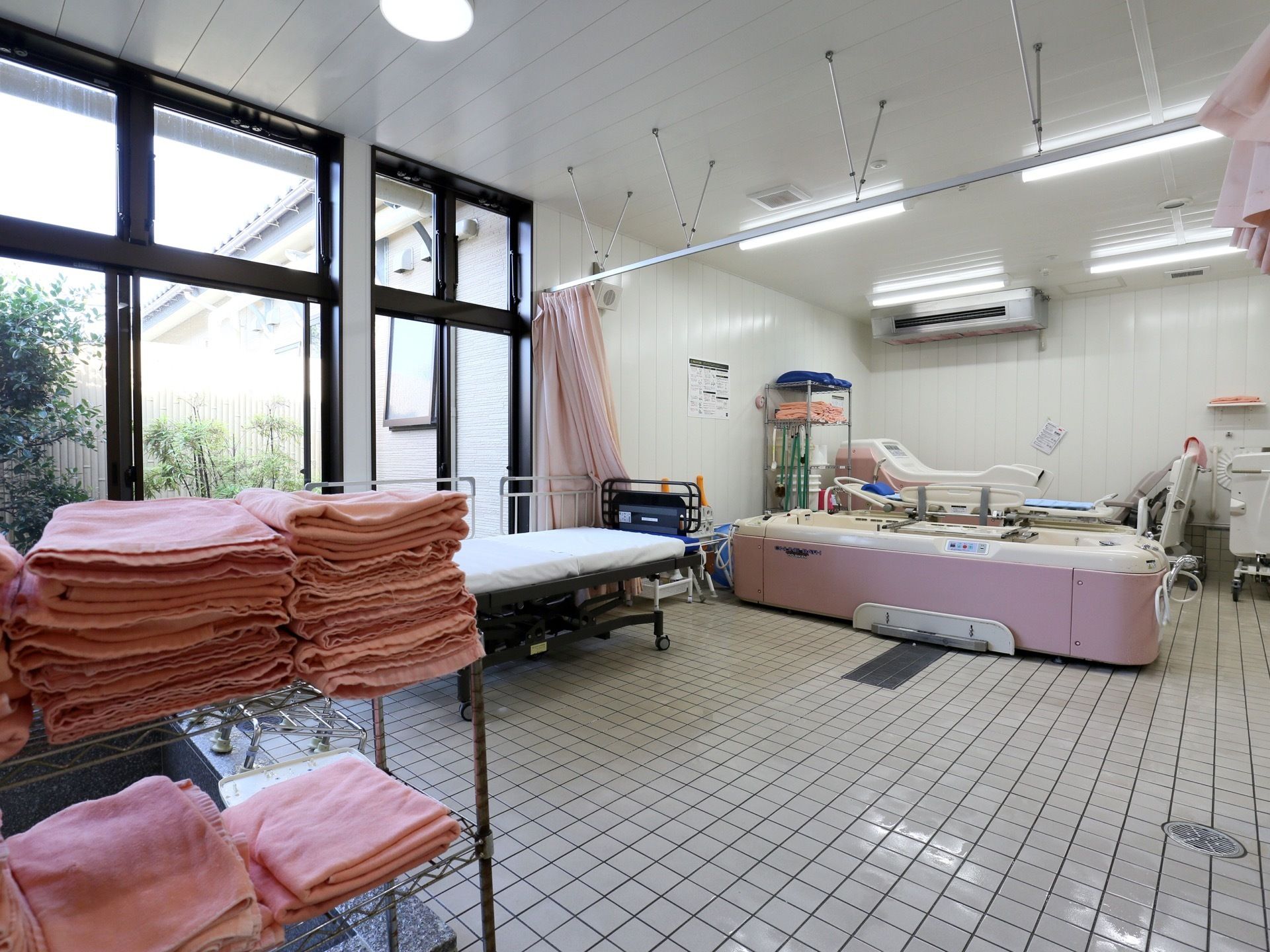 介護浴槽が設置されている。スタッフの介助のもと、ストレッチャーでそのまま浴槽に入ることができる。手前にタオルが用意されている。