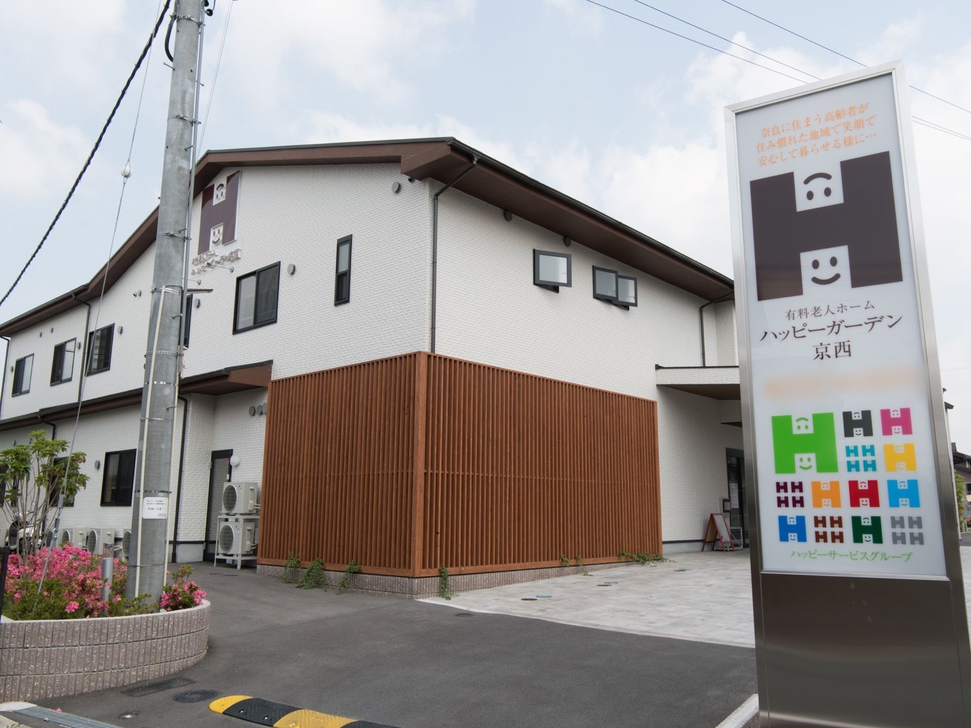 白色を基調とした外壁の２階建ての施設である。縦長の大きな看板が設置され、ロゴマークがいろいろな色でいくつも表示されている