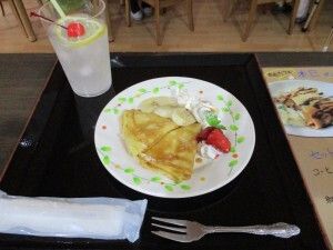 生クリームとバナナや苺を添えたパンケーキと、チェリーとレモンを浮かべたジュース