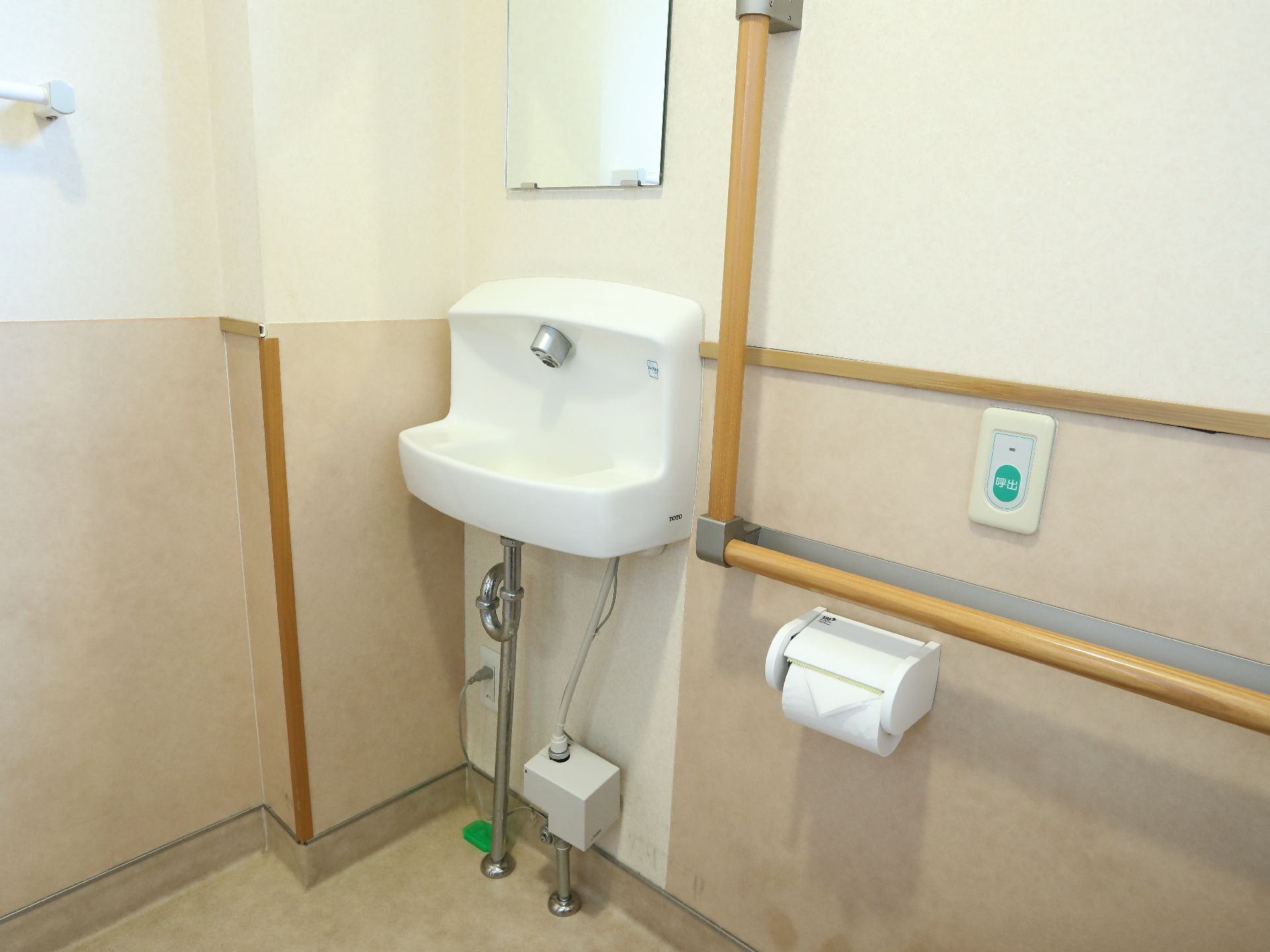 トイレには小さめの手洗い場が設置されており、その上には鏡が取り付けられている。壁にはL字型の手すりがついている。