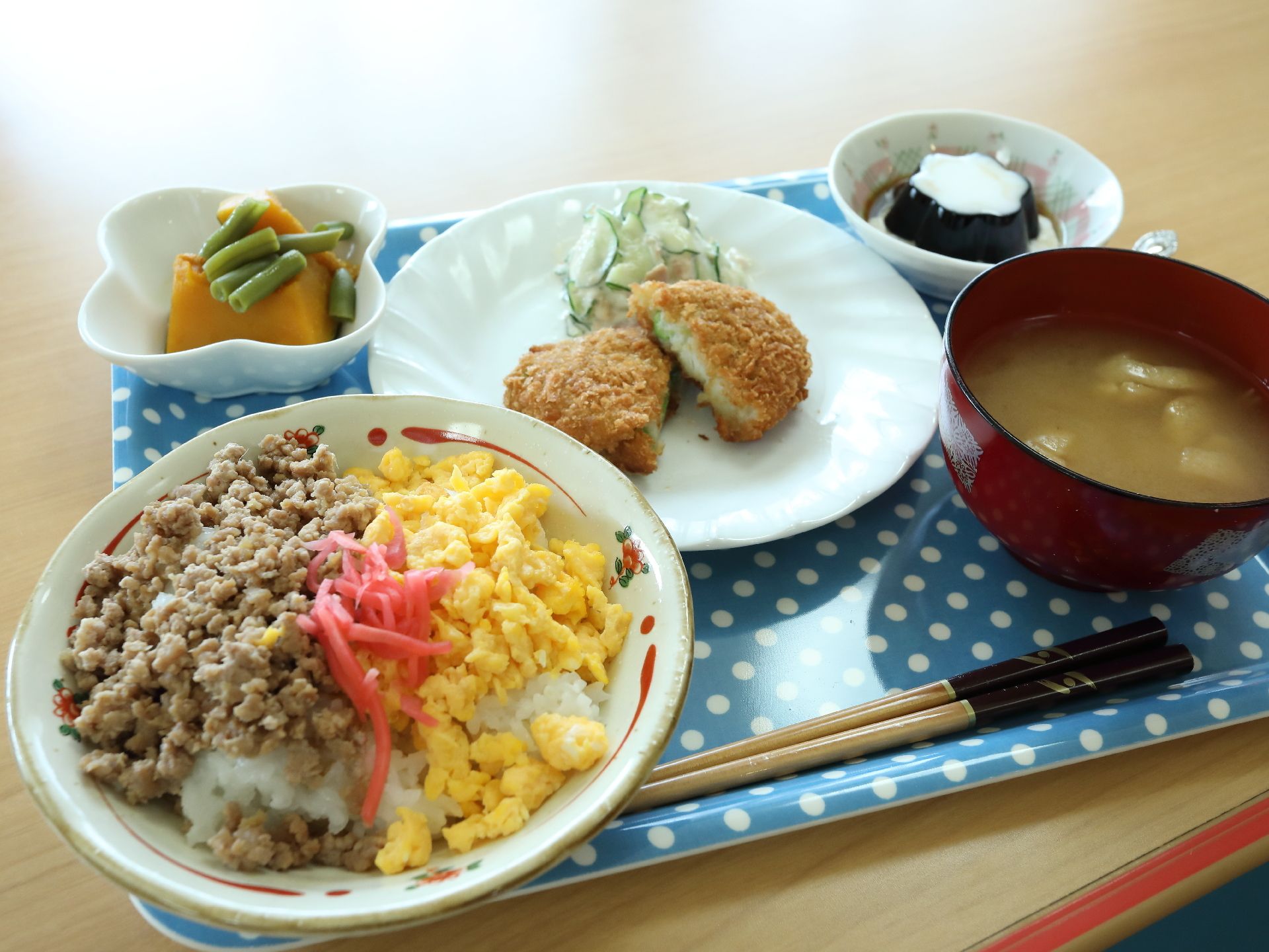 食事の一例。献立は、肉と卵のそぼろごはん、味噌汁、かぼちゃの煮物、コロッケとサラダ、そしてデザートにコーヒーゼリーがある。