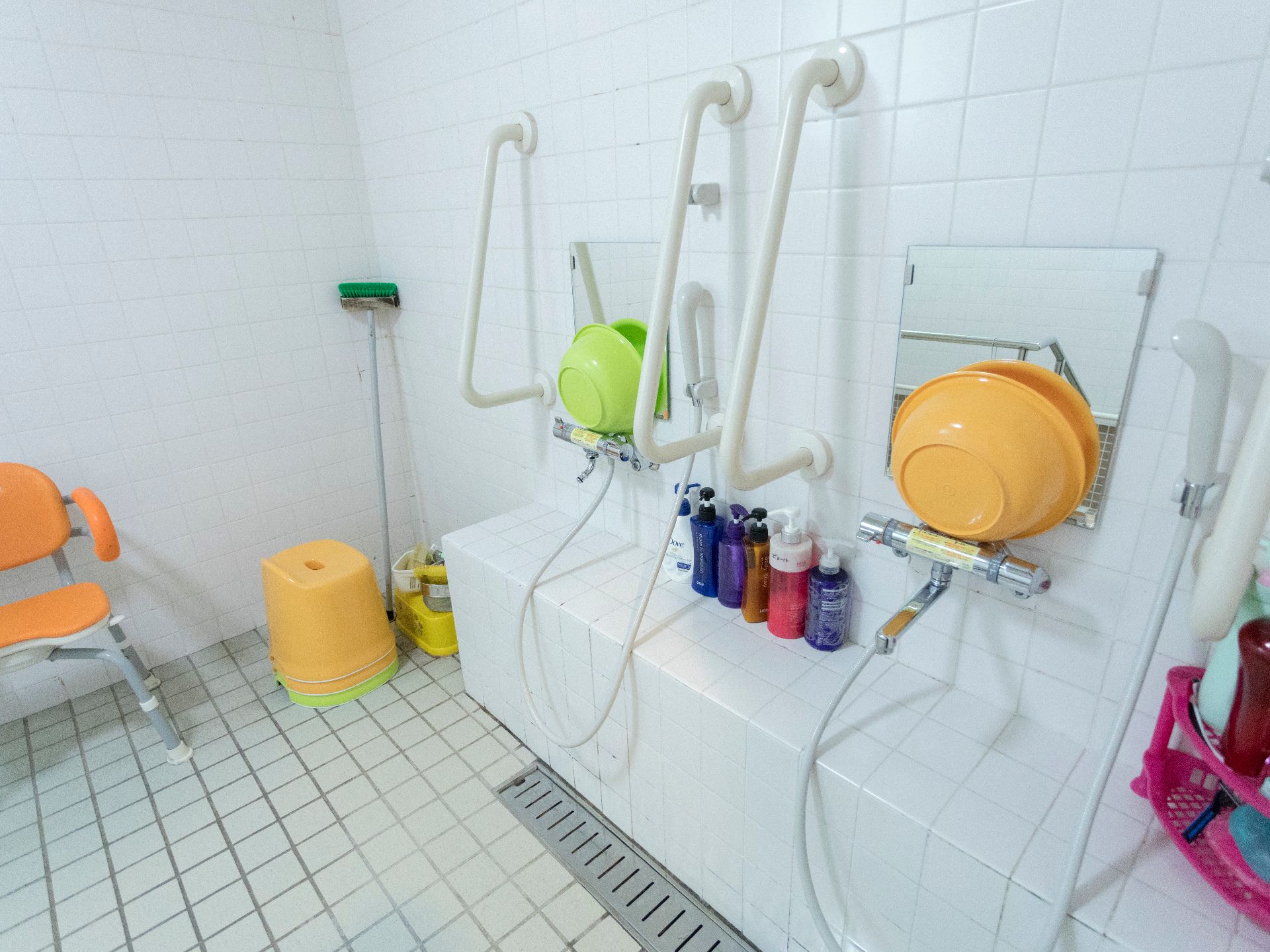洗い場の壁には鏡と手すりが設置ある。風呂椅子が用意されおり、座って身体を洗うことができる。シャンプーやリンスが完備されている。