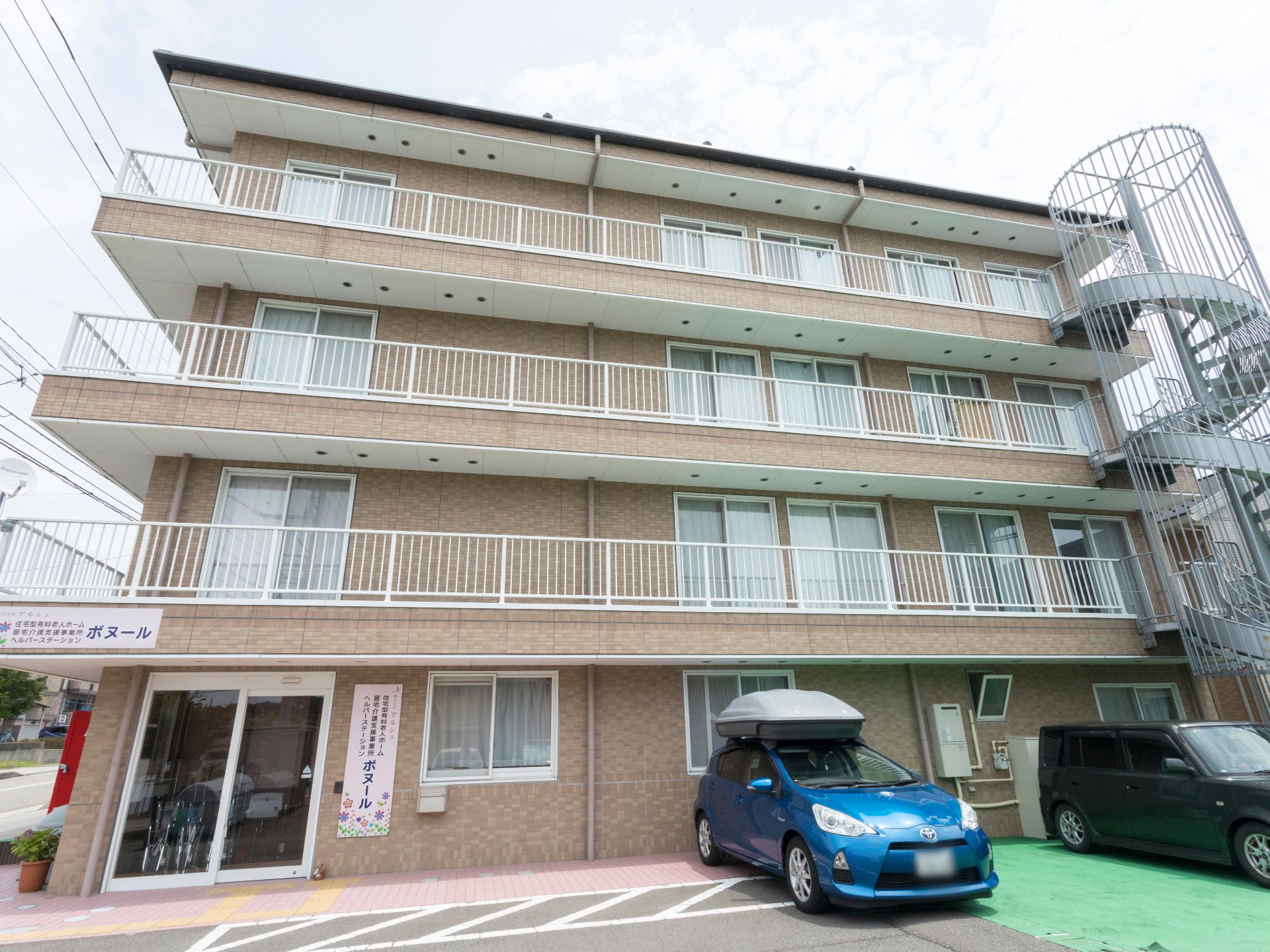3階建の施設で訪問介護ステーションが併設されている。建物の前に駐車スペースが設けられている。緊急避難用の螺旋階段が設置されている。