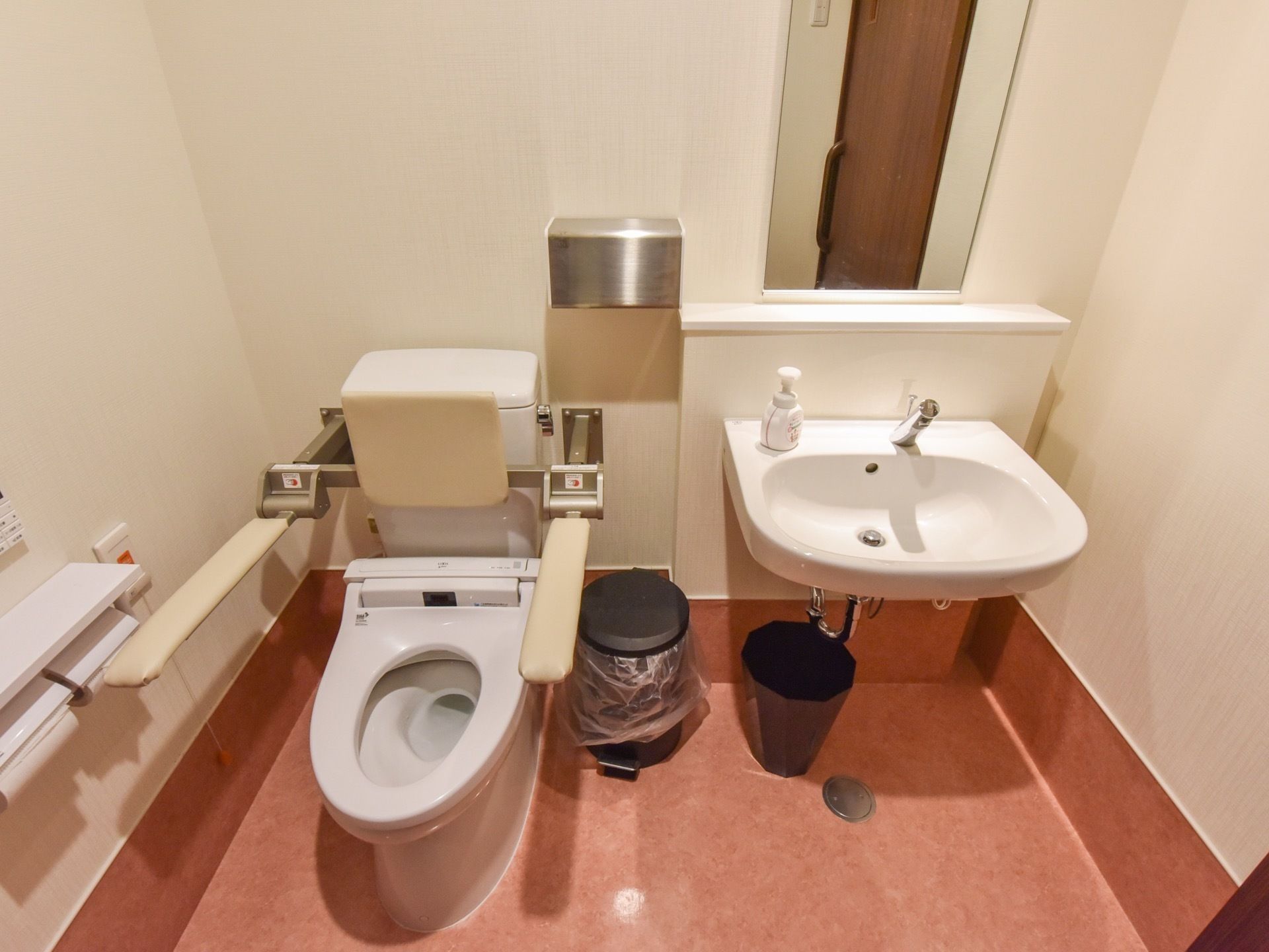 清潔感のあふれる白を基調としたトイレである。鏡と洗面台が設置されており、扉はスライド式になっている。
