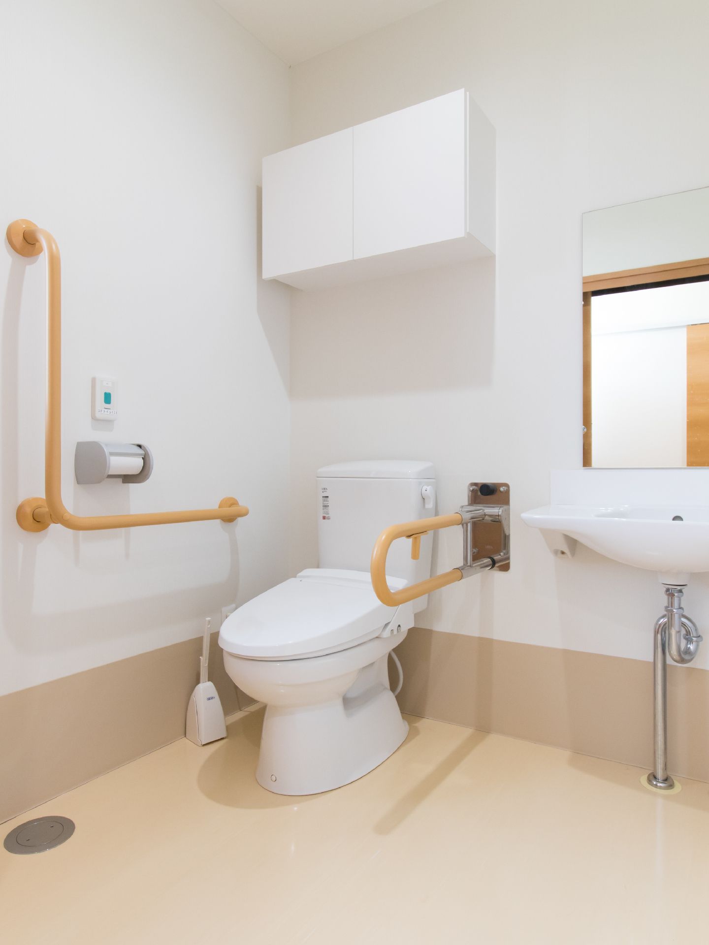 トイレと鏡付きの洗面台が設置されている。洋式便器側には2つの手すりが付いている。トイレ掃除用のブラシもある。