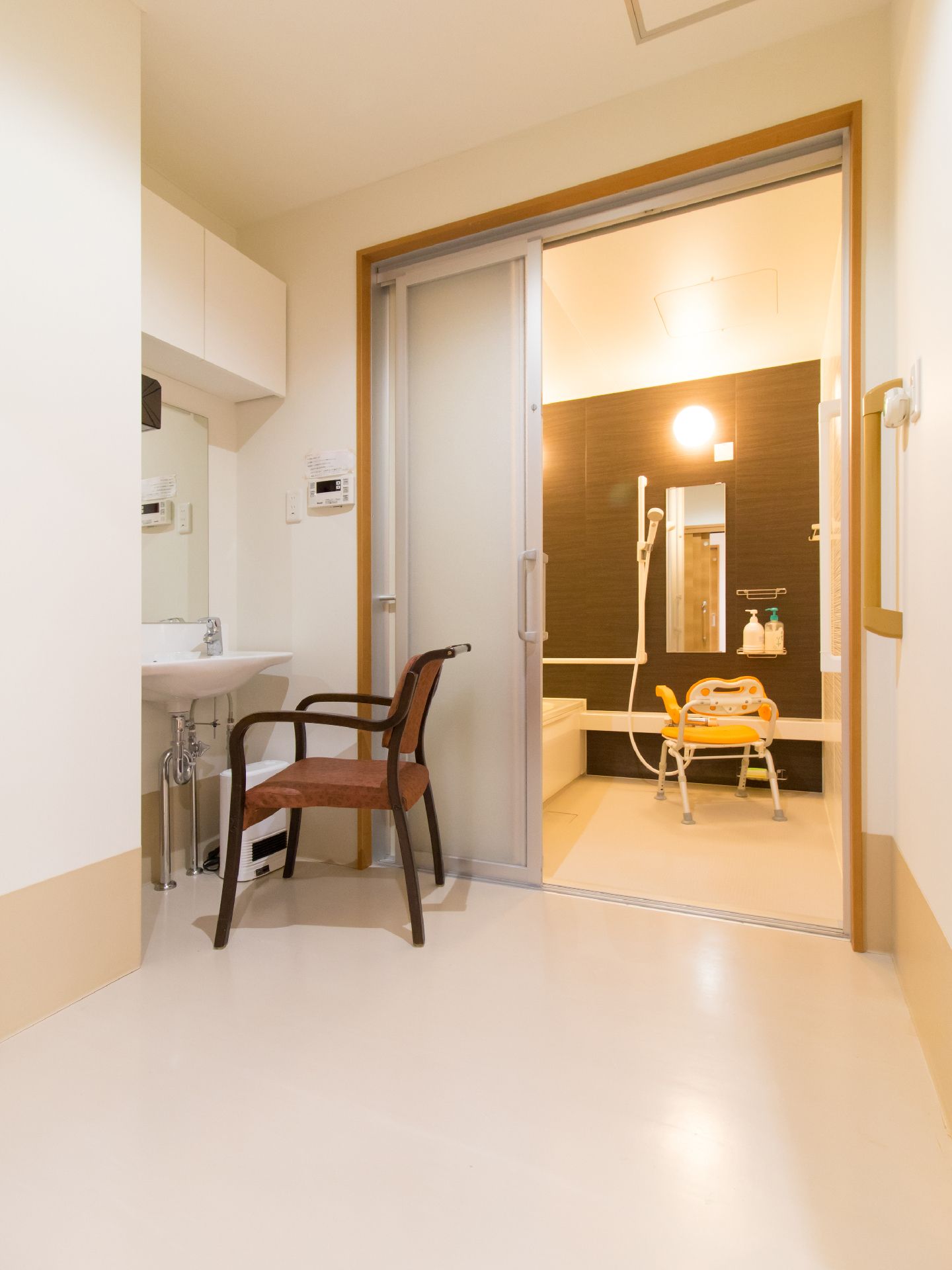 脱衣所と浴室を隔てる扉は利用しやすい引き戸を採用している。洗面台の前にはゆっくりと休憩もできるイスを完備している。