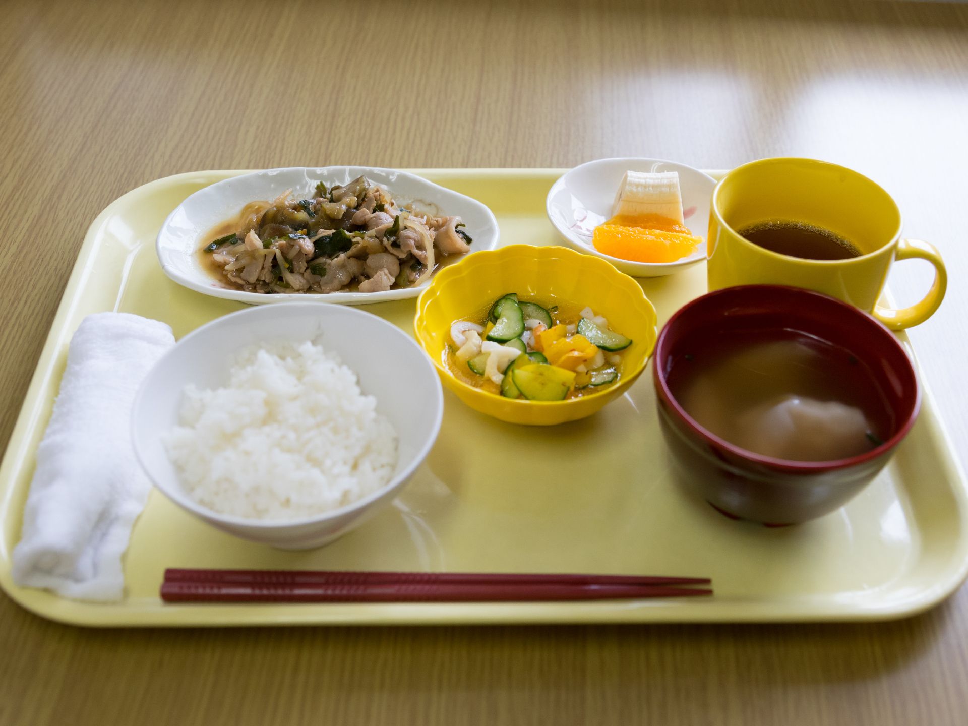 野菜が多めの栄養バランスのとれたメニュー。飲み物はお茶で、デザートにバナナとみかんが準備されている。