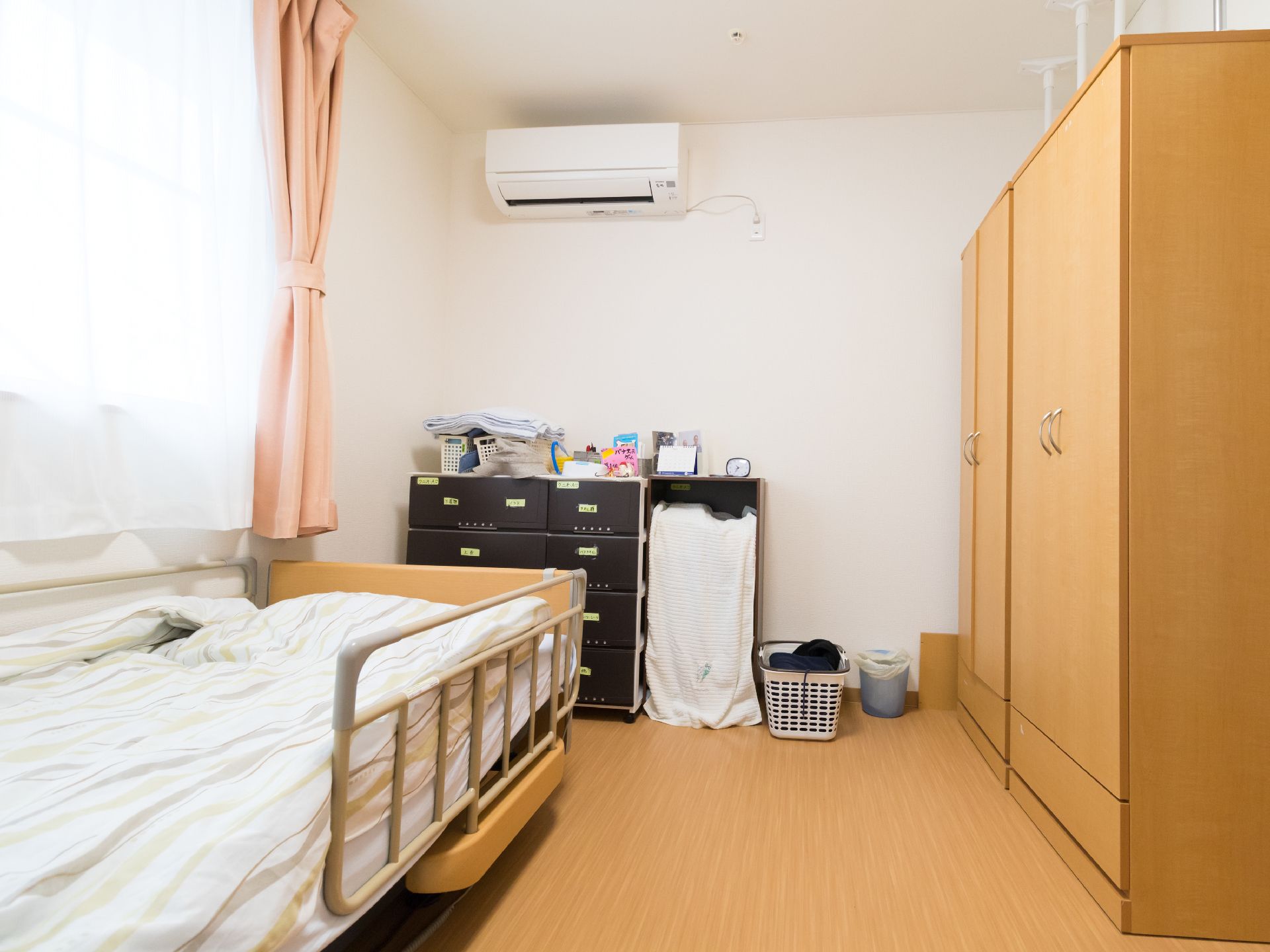 居室内のベッド足元には、引き出し付きのタンスがある。ベッドの向かい側には、クローゼットが2台設置されている。