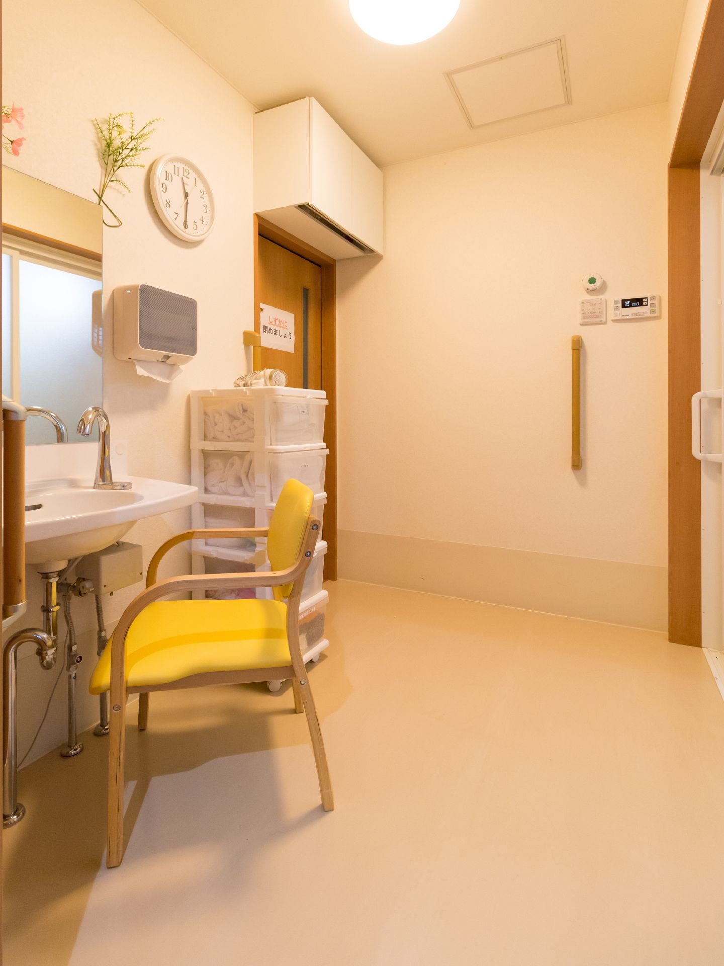 洗面台は腰を掛けて使用することができる。鏡とティッシュホルダーが設置されている。壁には縦向きの手すりが設けられている。