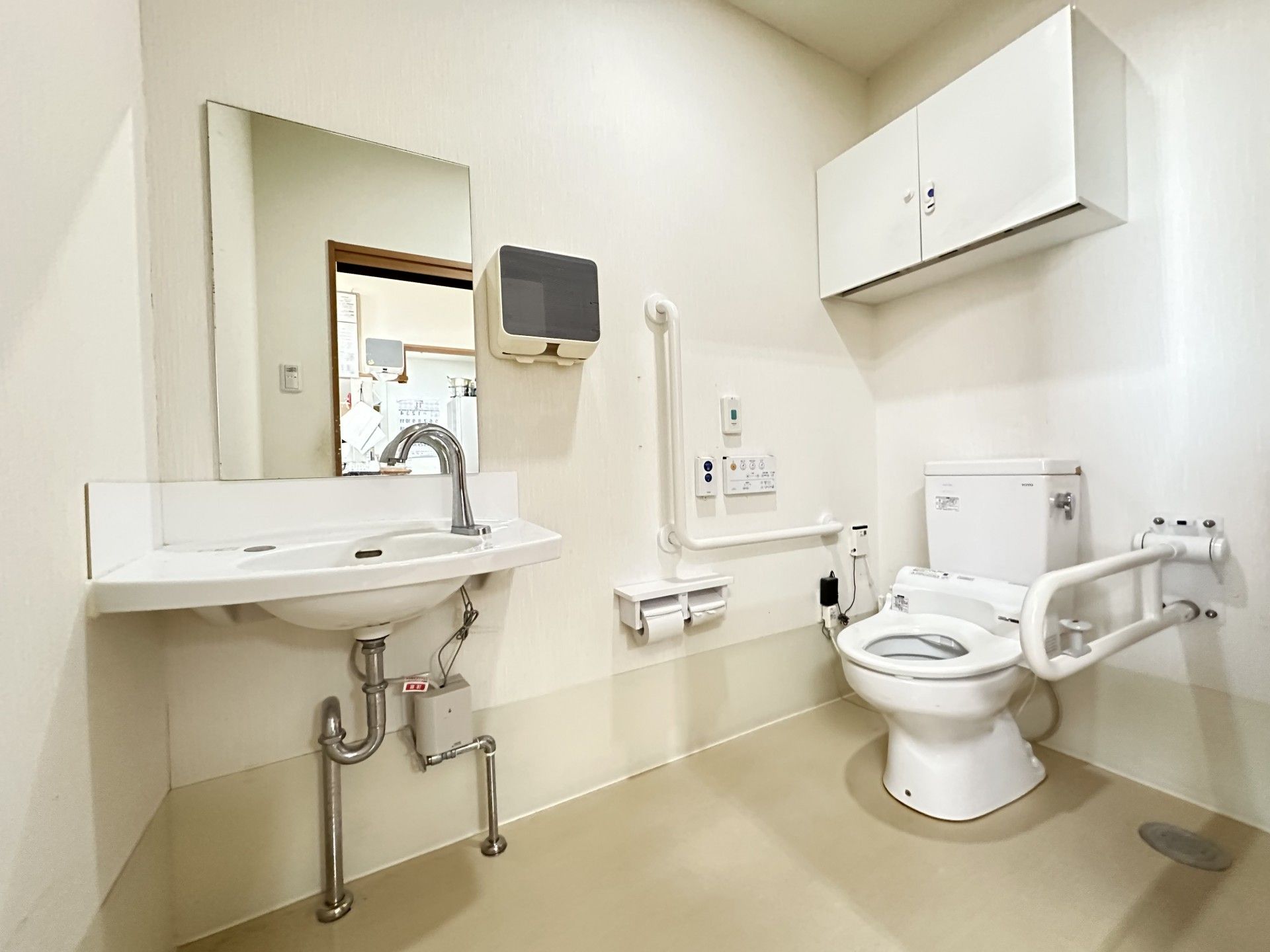 トイレの壁には、手すりとナースコールがついている。右手には、移動が可能な手すりがある。上方に小窓があり、棚もある。