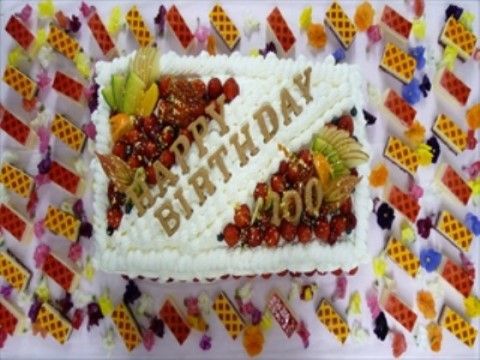 白い生クリームとフルーツを乗せた100歳を祝うバースデーケーキ