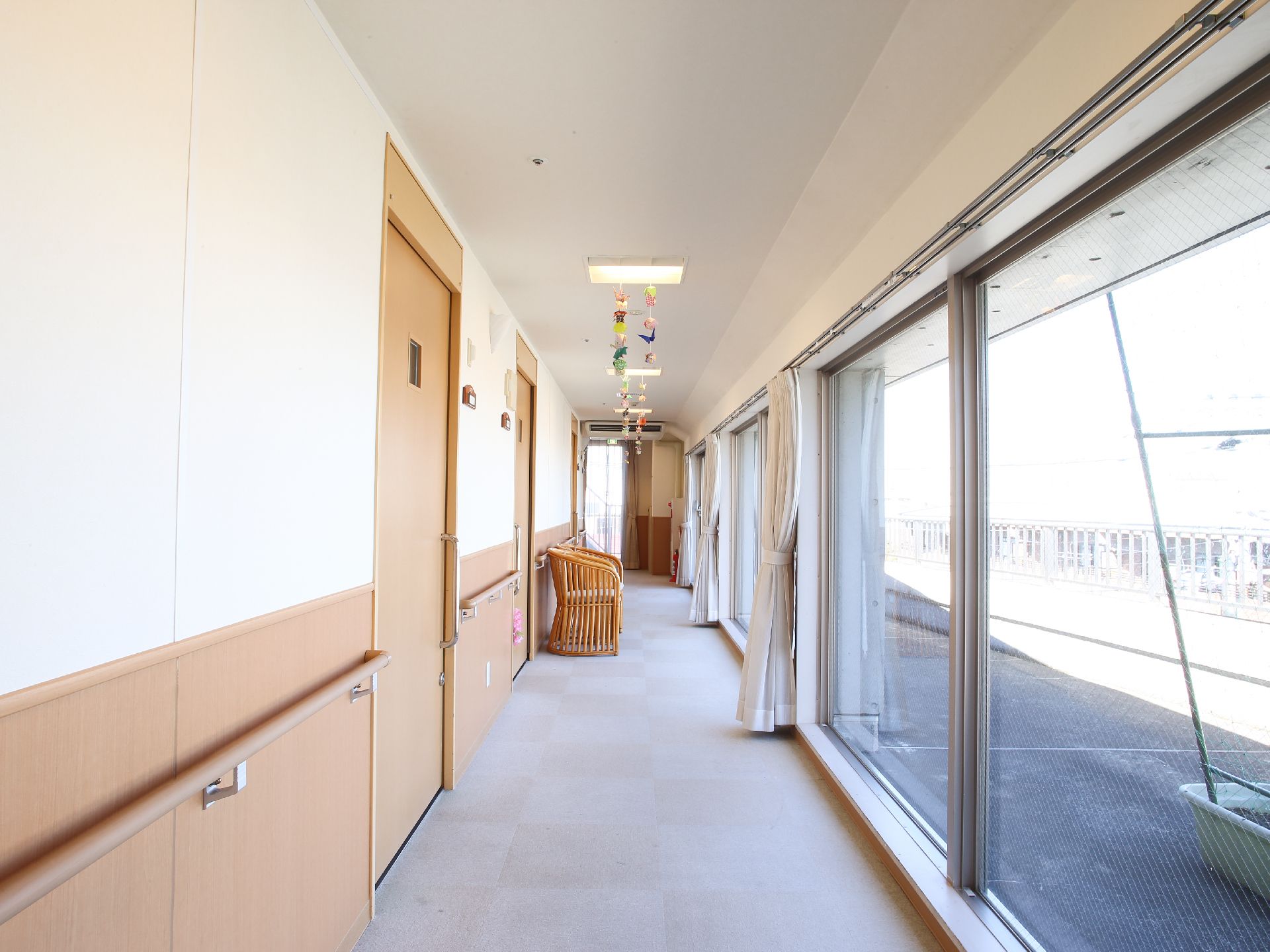 廊下は広々としており、窓が大きいので、カーテンを開けておくと光が入ってとても明るい。壁には手すりがある。