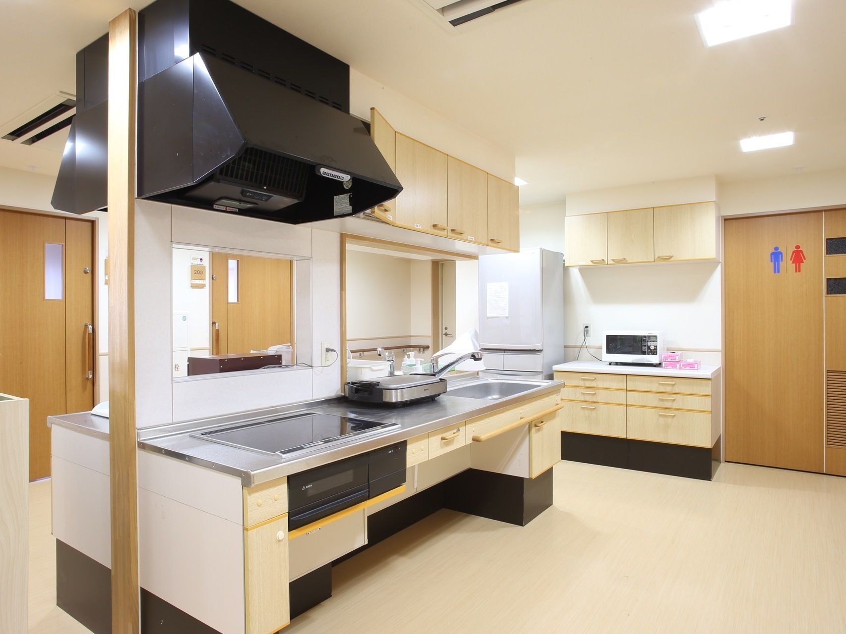 オープンキッチンには電磁調理器が設置されている。料理に火を使わないため、安全である。奥のカウンターにはレンジが置かれている。