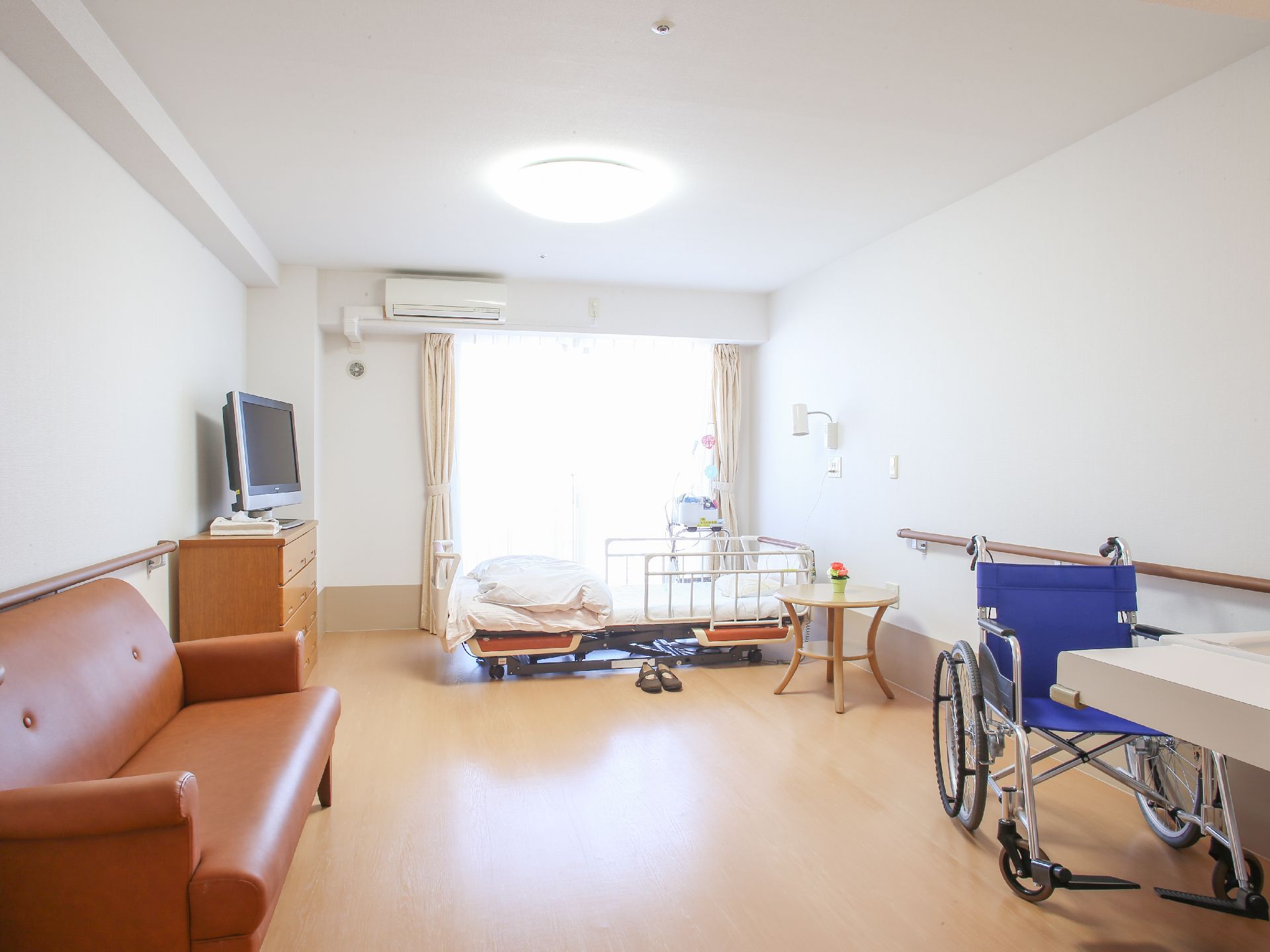 居室には、介護用のベッドが窓に対し平行に置かれている。壁にはしっかりとした木製の手すりが取り付けられている。