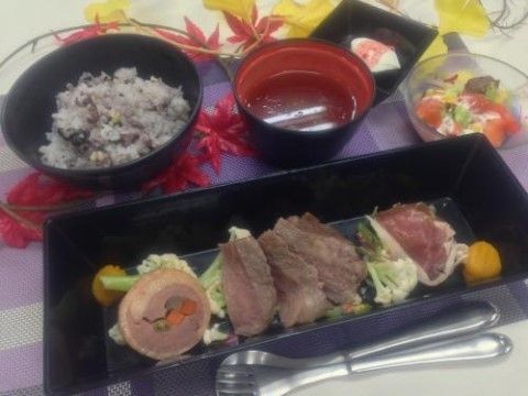 奥に雑穀米のご飯と汁物、手前には肉料理が並ぶ食事