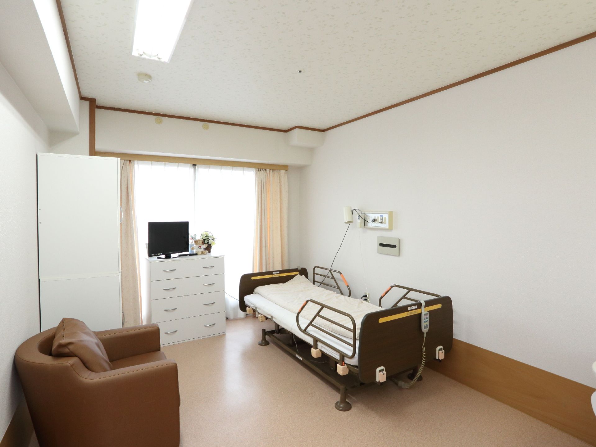個人用の居室には介護用ベッド、ソファ、収納棚、テレビが備わっている。また2重のカーテンが付いているので日照を調節できる。