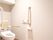白い壁とベージュ色の床の内装のトイレに洋式便器がある。壁に長い紐がついたナースコールが取りつけられている。