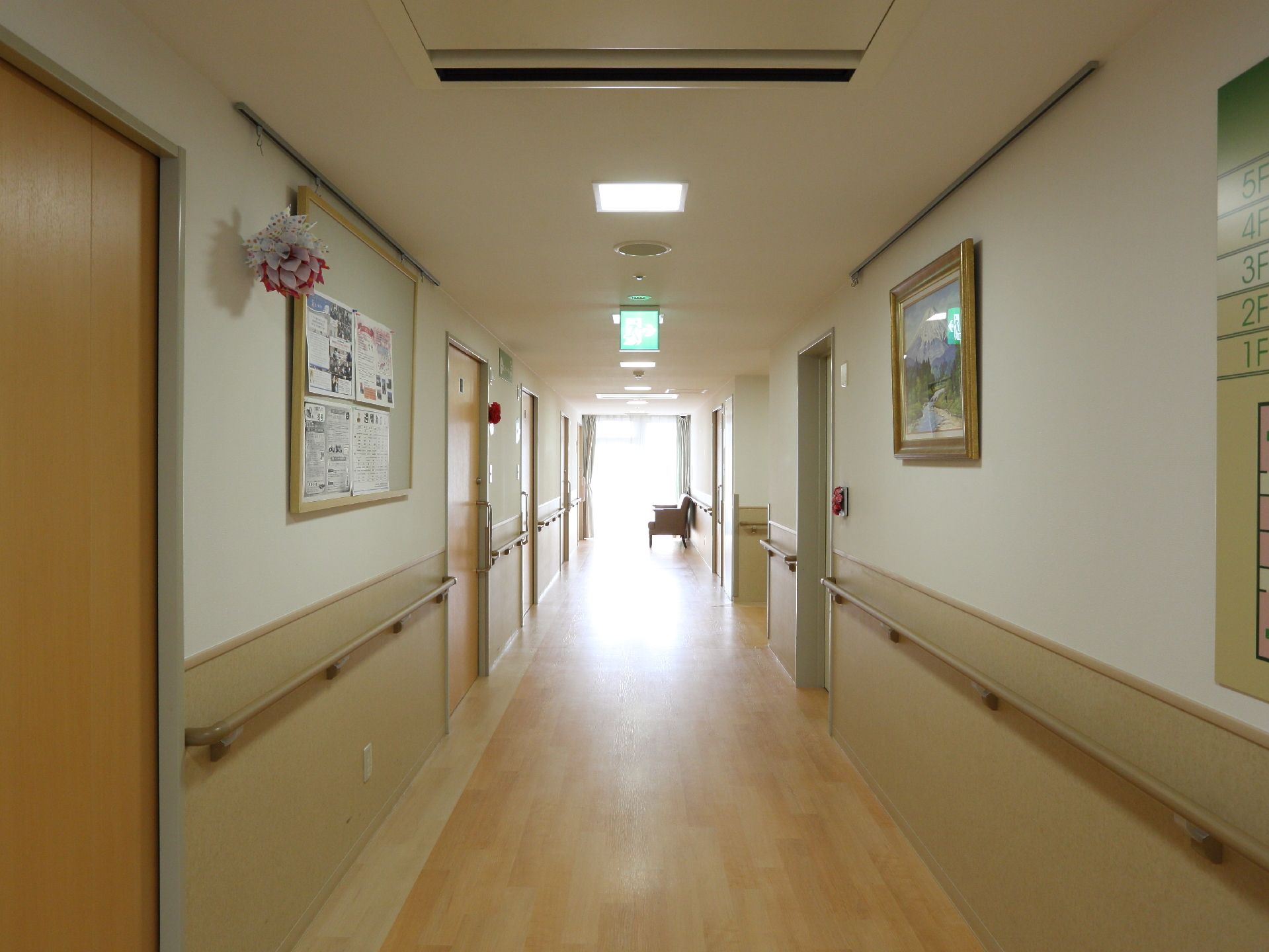 居室をつなぐ廊下はフローリングになっていて、壁には手すりが設置されている。また、お知らせが掲示されたり、絵画が飾られている。