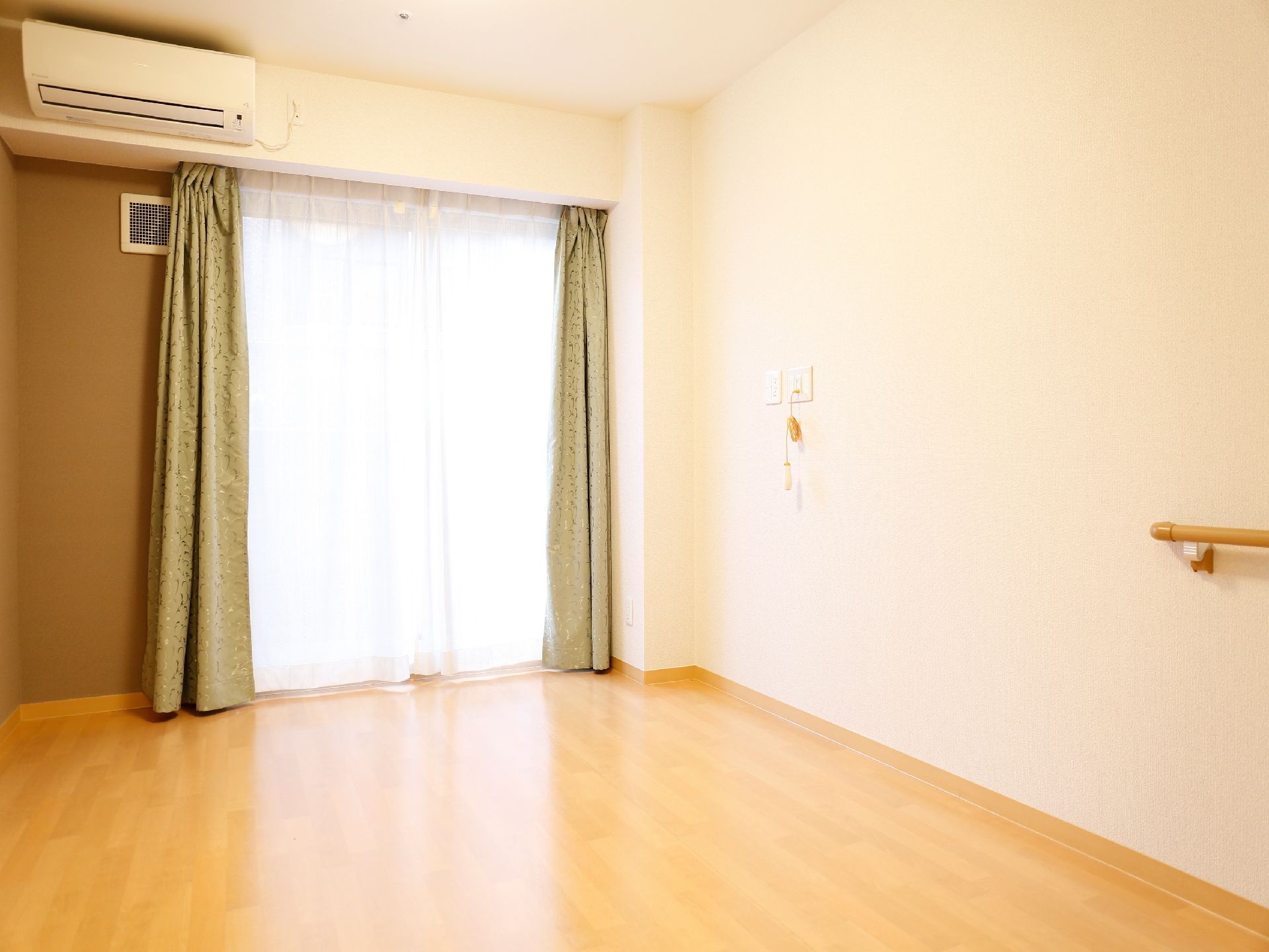 緑のカーテンがかかっている居室。白と茶色の内装に合っている。