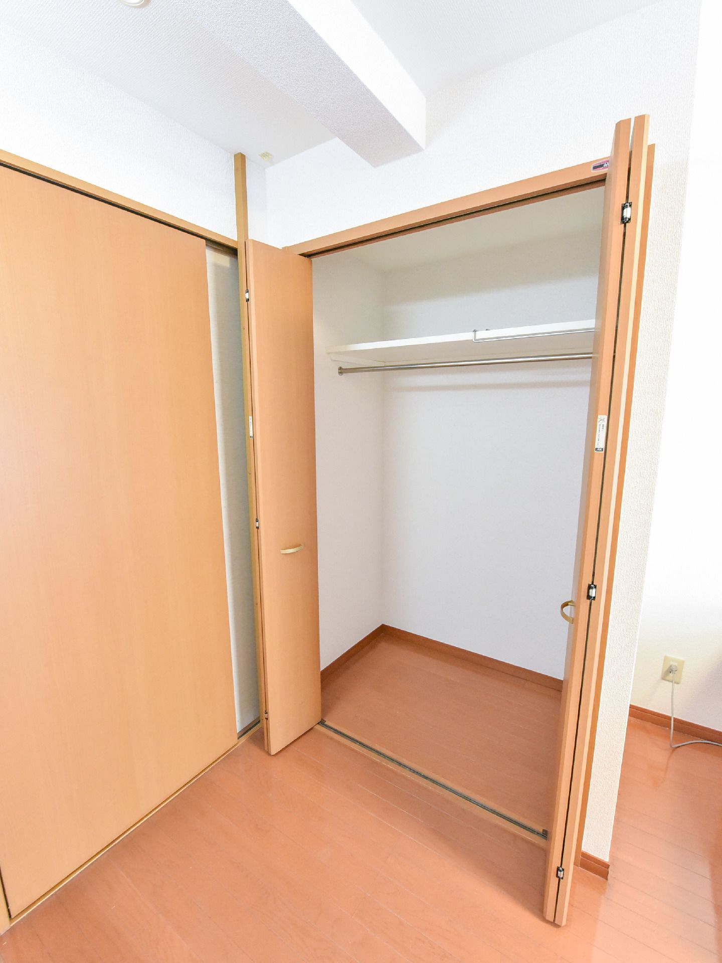 クローゼットは両開きで、十分な量のハンガーをかけることができる。外装は木目で、開けると白が基調になっている。