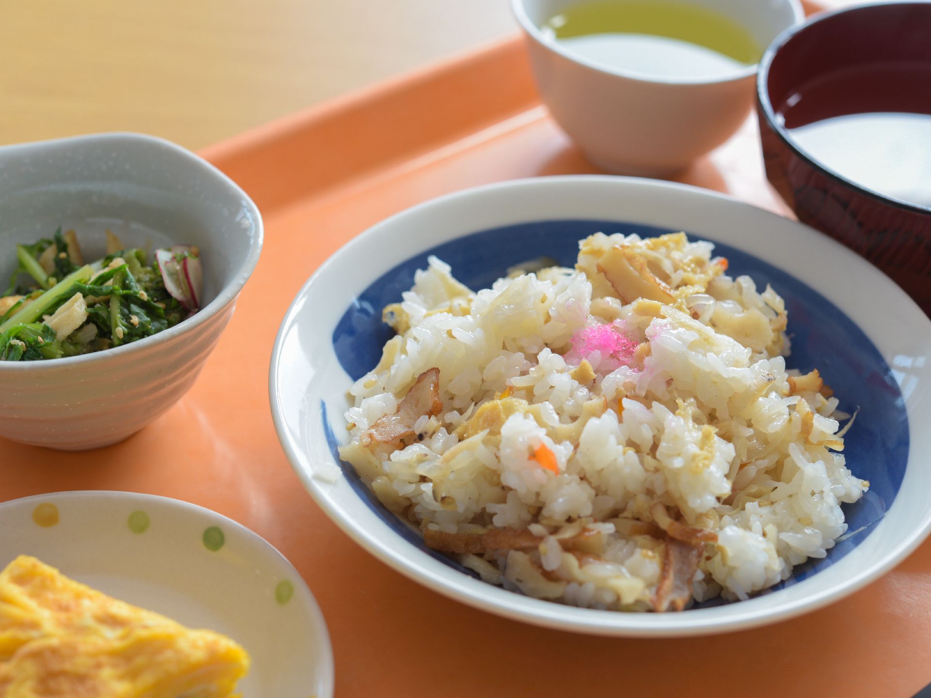 トレイの上に食事として3皿。その他に汁椀とお茶が用意されている。トレイはオレンジで落ち着いた色合いである。