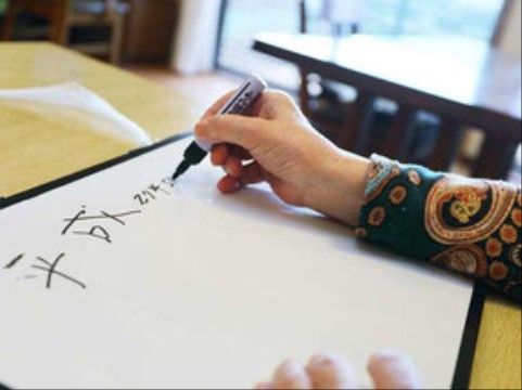 ホワイトボードに黒いペンで、日付を書き込む入居者様の様子