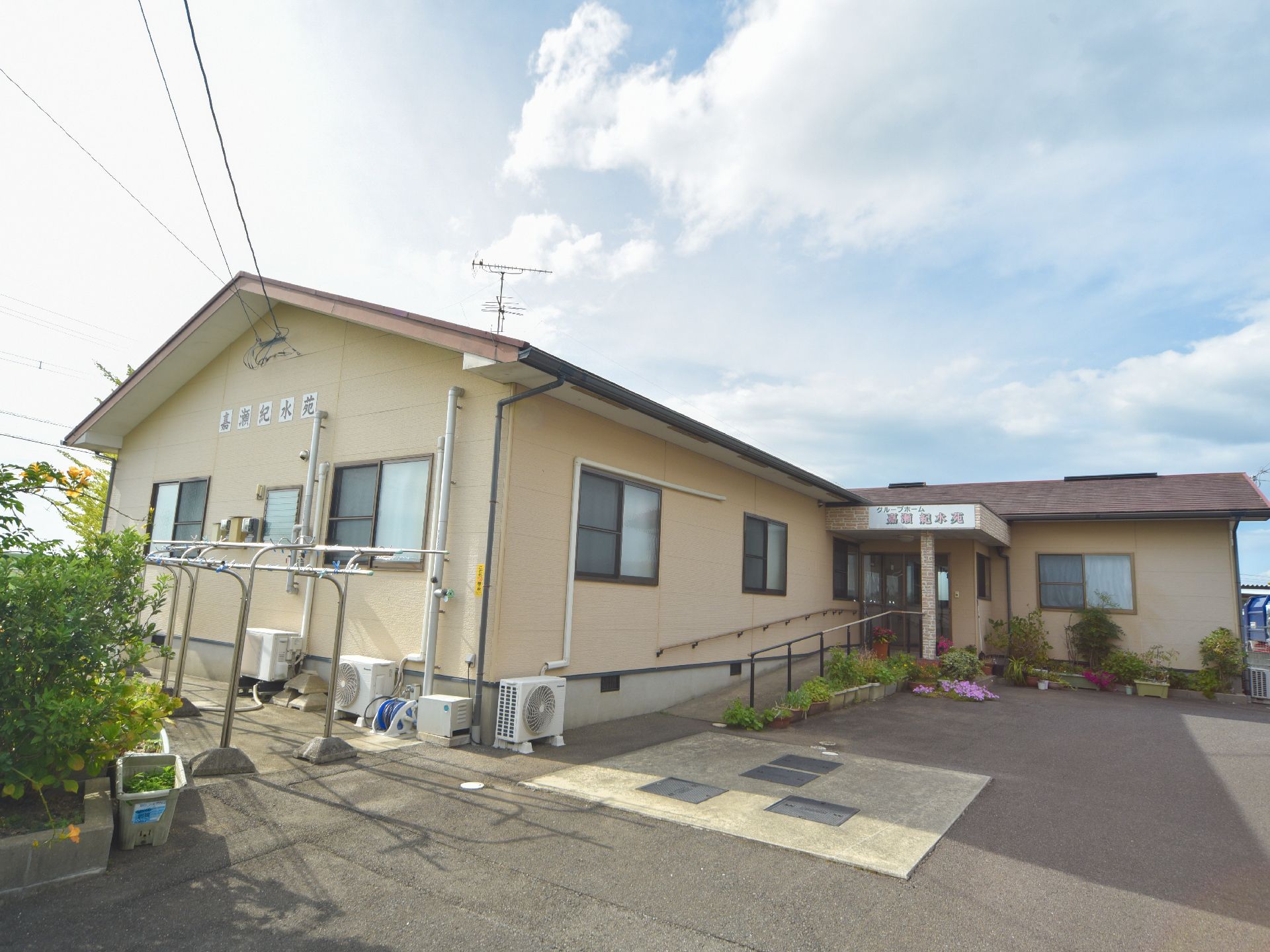 施設の正面側には窓が6つ設置されている。画像奥に位置する石造りのスロープ横には植物の植えられたプランターが数点並べられている。