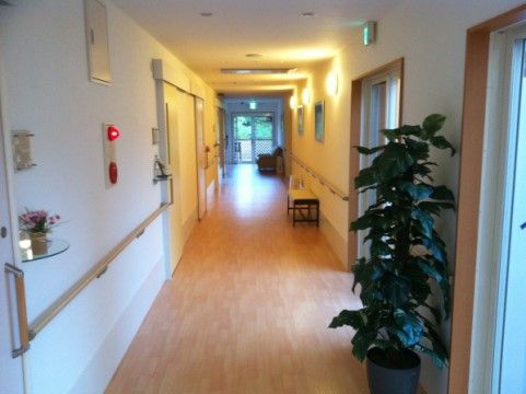 廊下の壁は白を基調にしており、花が飾られた棚や非常ベルが設置されている。ドア部分を除いて手すりが付けられている。