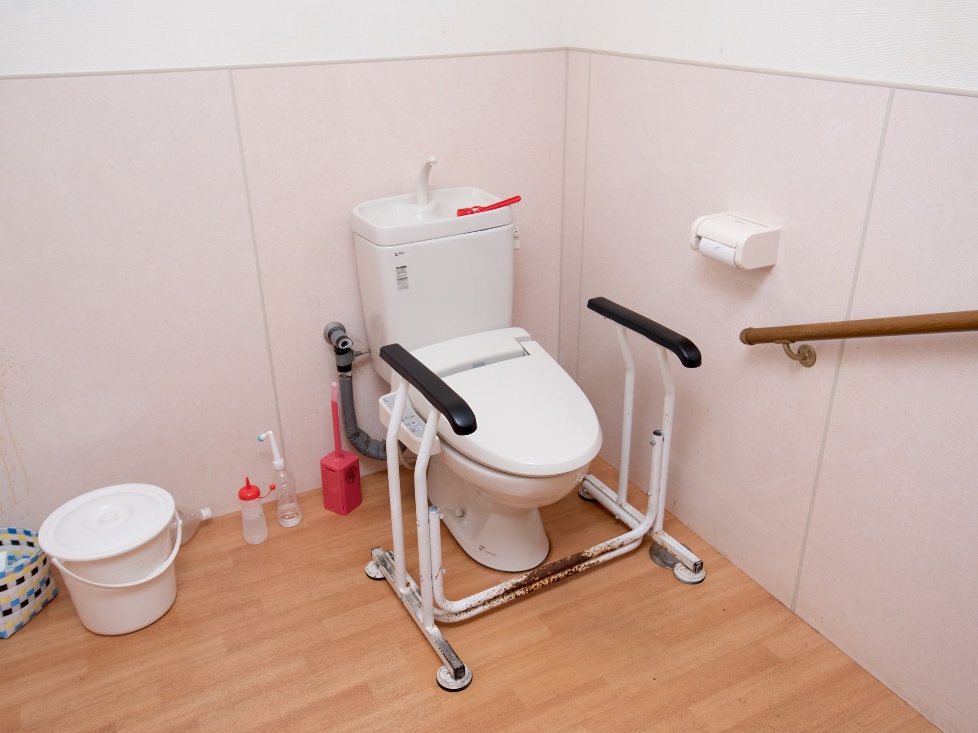 トイレの便器の前には金属製の手すりが置かれている。入居者様は使用状況に応じて移動させることができる。