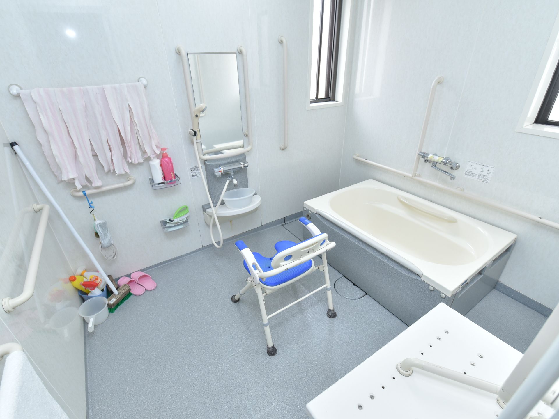 壁に設置されたタオル掛けに複数のタオルがかかっている。前面に縦長の鏡があり、椅子が１脚置かれている。