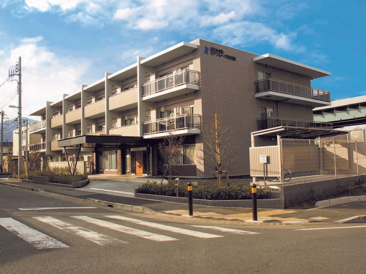 上階にベランダが設置された、ベージュ色の大きな施設の外観