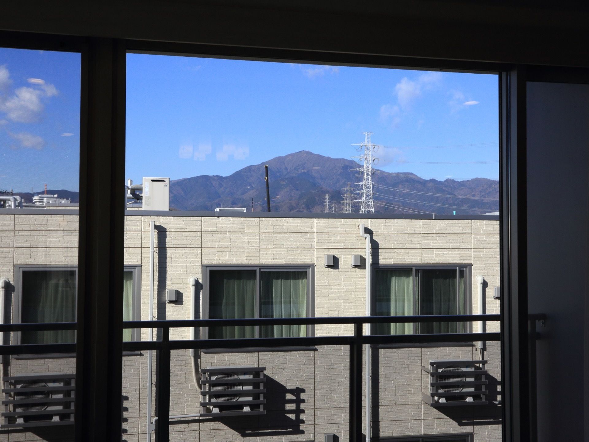 窓の外には、室外機が置かれている。周辺に大きな建物はなく、ダイナミックな山の景色を見ることができる。