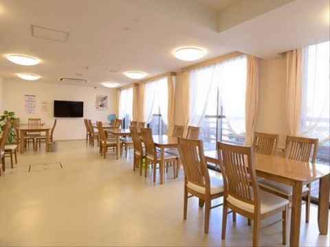 開放的なリビングには入居者様同士で歓談できるよう４人掛けのテーブルが並んでいる。車椅子をご利用の方でも移動しやすい空間である。