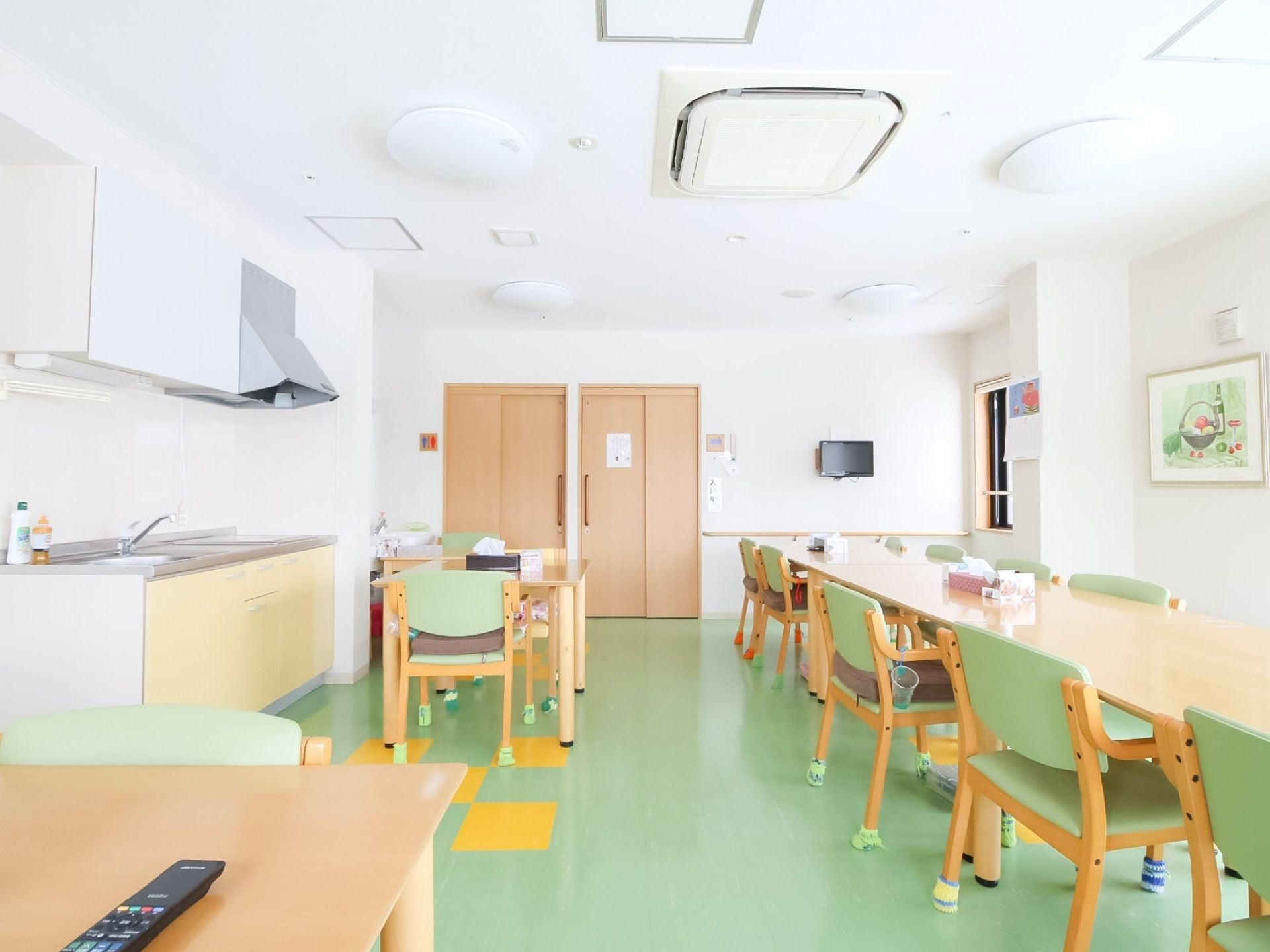 縦長にテーブルと椅子がある広い食堂がある。床は緑色になっており、壁には額縁に入った絵が飾られている。