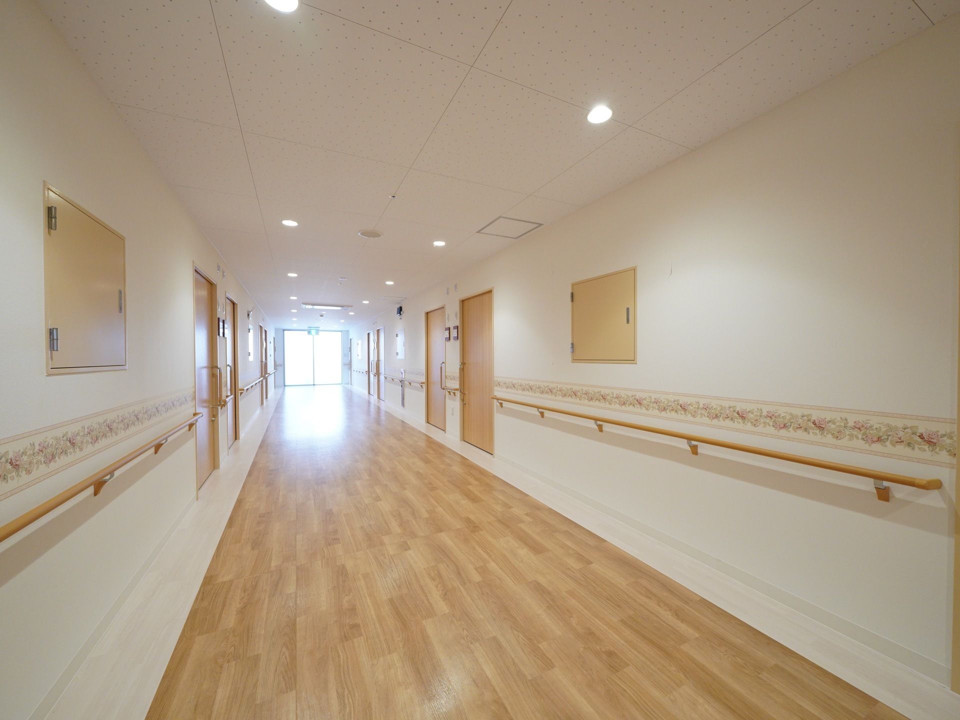 昼間は廊下まで光が差し込むような明るい色合いの室内。手すり、スライドドア、幅の広い廊下と入居者様の安全な生活をサポートしている。