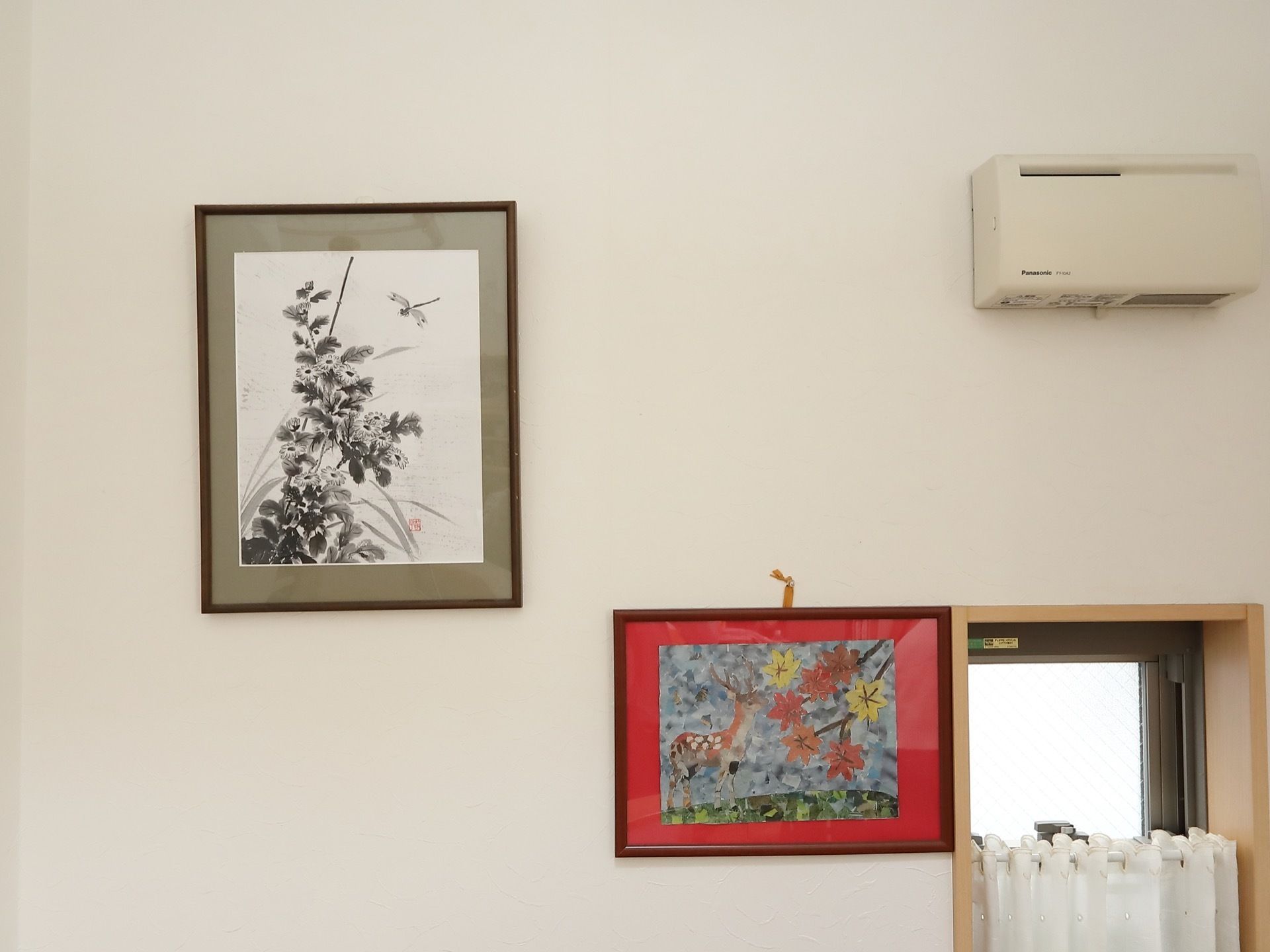 額縁に入れられた絵が壁に掛けられており、トンボ、鹿、カエデなどが描かれている。絵の横には小さな窓がある。