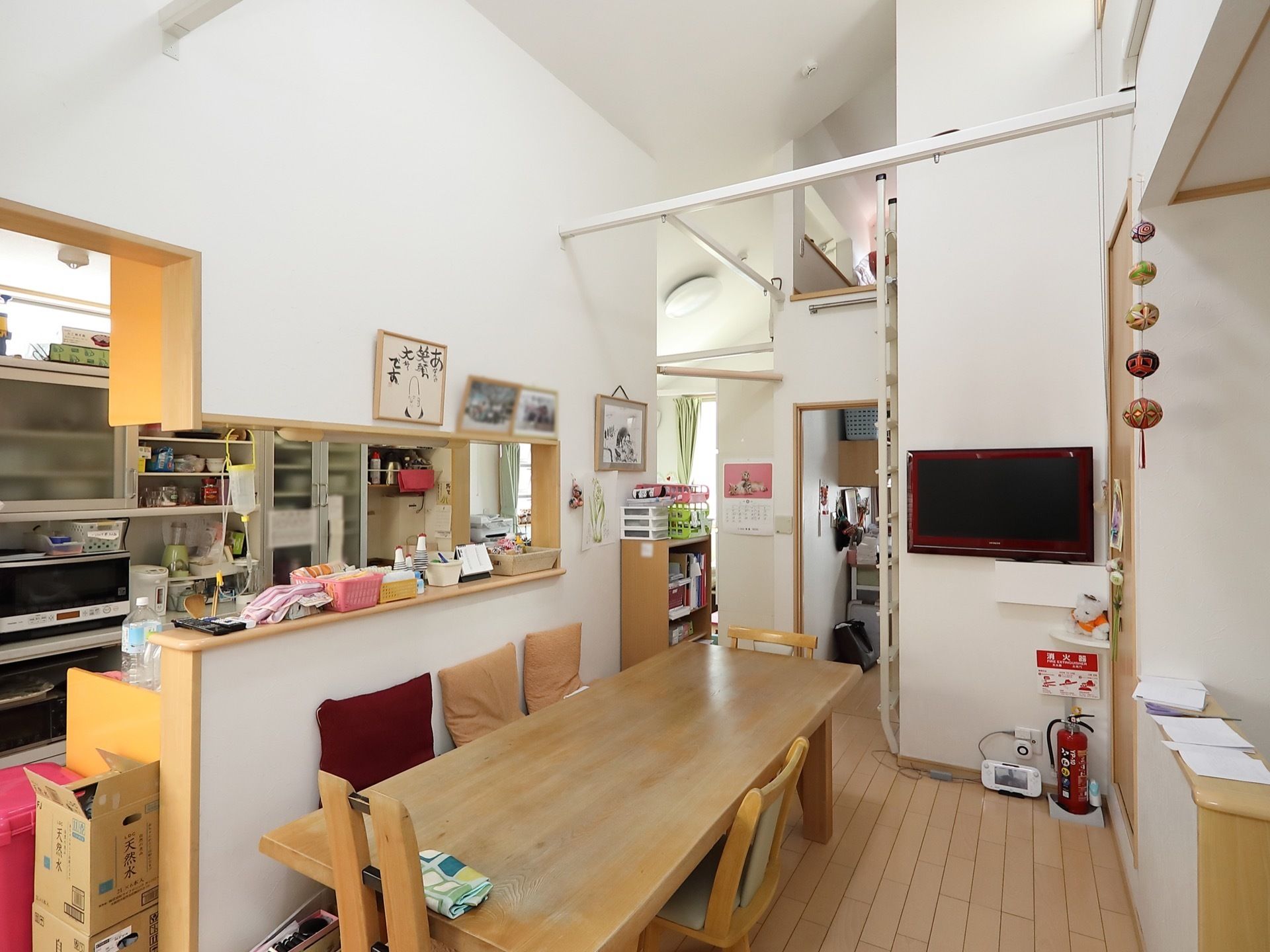 共有スペースにはテーブル、椅子、テレビなどが設置されている。部屋にはキッチンも完備されており、カウンターにはさまざまな小物が置かれている。